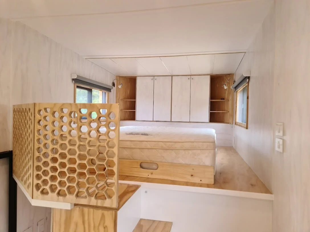 The top of the staircase is adorned with a custom hexagonal design privacy screen and roof shutters slide open to reveal the skylight for some stargazing in bed. Even more shelved cupboard space with built in bedside tables at the head of the bed.
