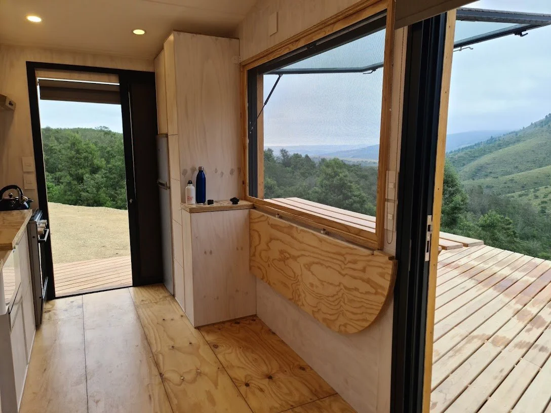The staircase serves for loads of utility space and houses the laundry accessible from the outside of the CaveLet tiny house. The inside-out bar counter lives out onto a 50 square meter hardwood deck and flips down on the inside the tiny house for s