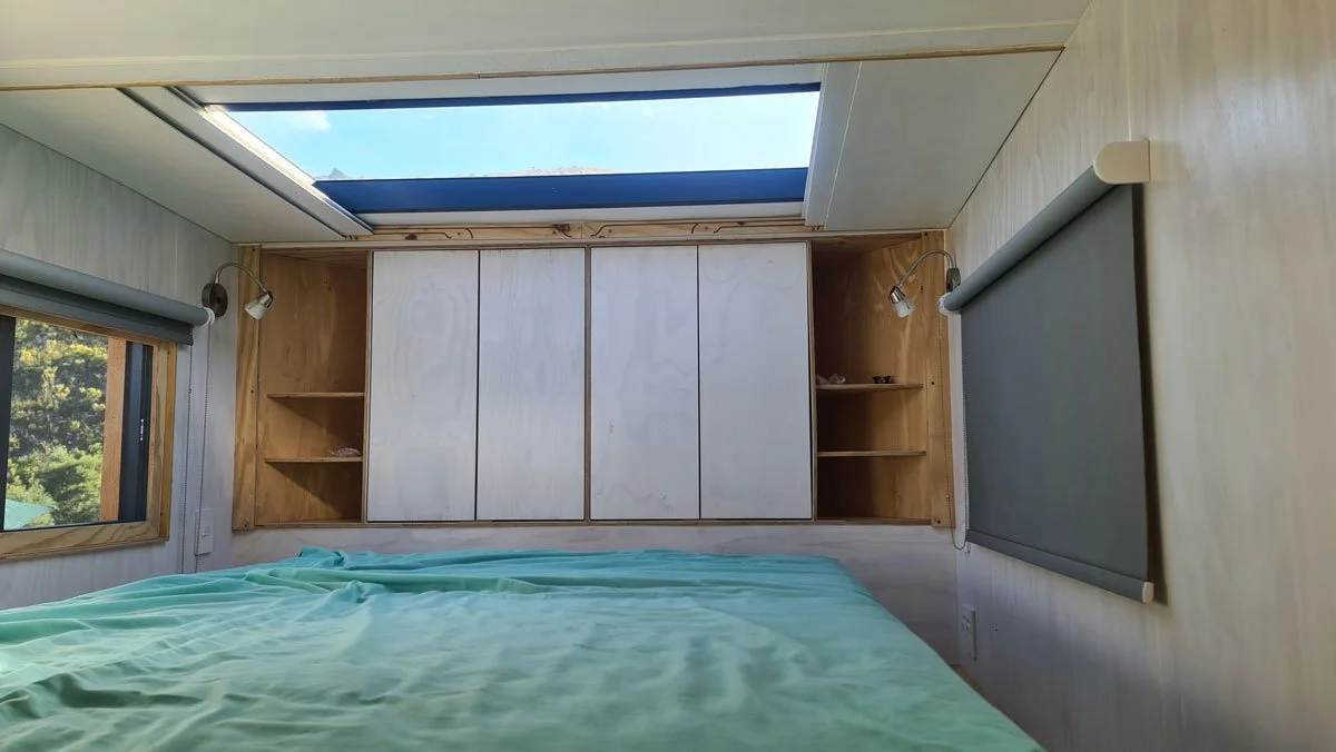 The top of the staircase is adorned with a custom hexagonal design privacy screen and roof shutters slide open to reveal the skylight for some stargazing in bed. Even more shelved cupboard space with built in bedside tables at the head of the bed.