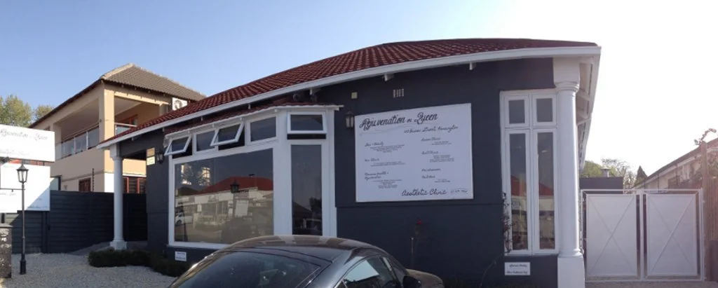 A gray building with white trim and a red roof, featuring a large sign on the front advertising a restaurant named 'Rejuvenation and Queen'.