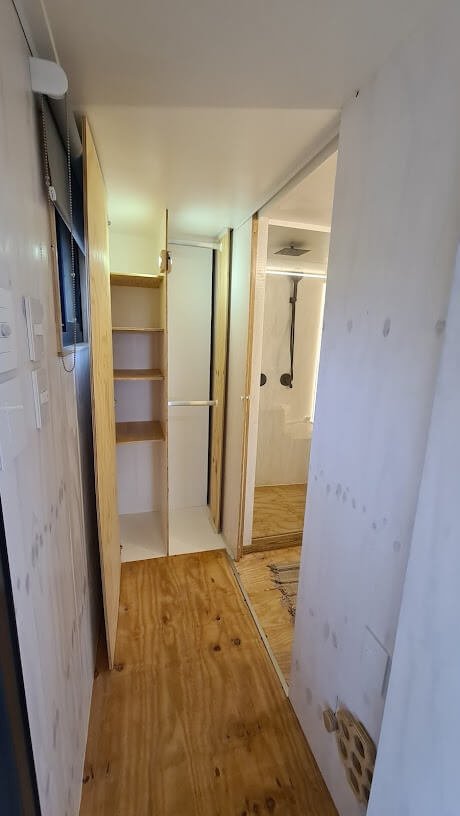 More cupboard space for clothes in the passage which serves as a dressing room adjacent to the tiny house bathroom.