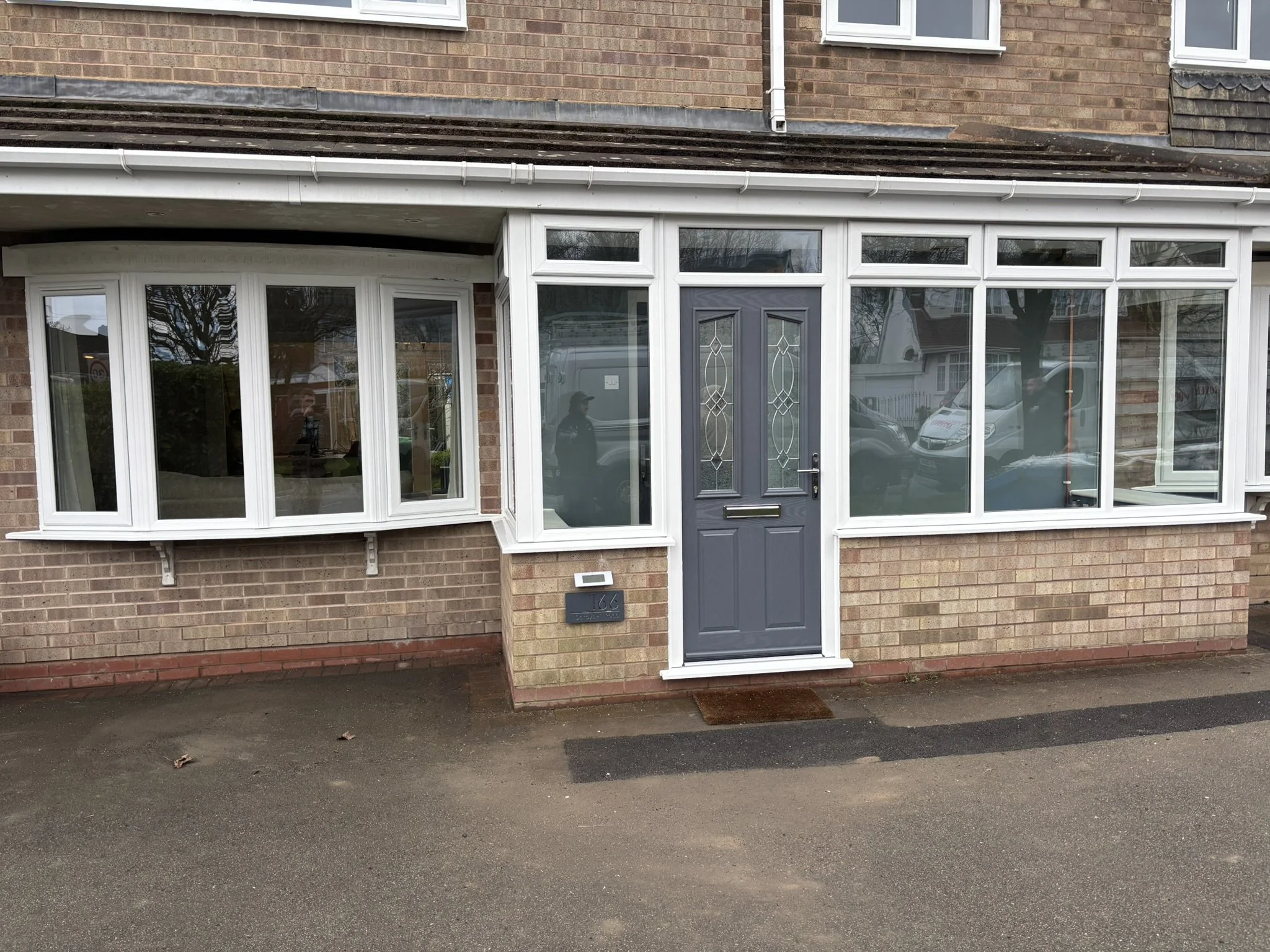 Front view of a brick house with a porch, featuring a blue front door and large front windows.