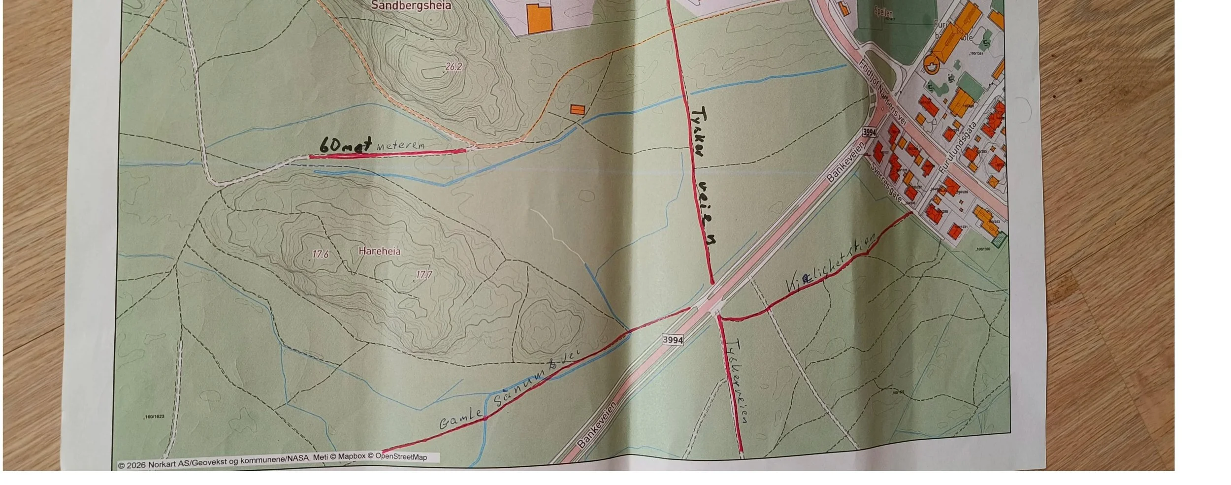 Et kartskisse som viser ulike veier og stier i et område med navnene Tyskerveien, 60.meteren, og Sandbergsheia. 
Kartet inkluderer bygninger, veier, vannkilder og topografiske detaljer.