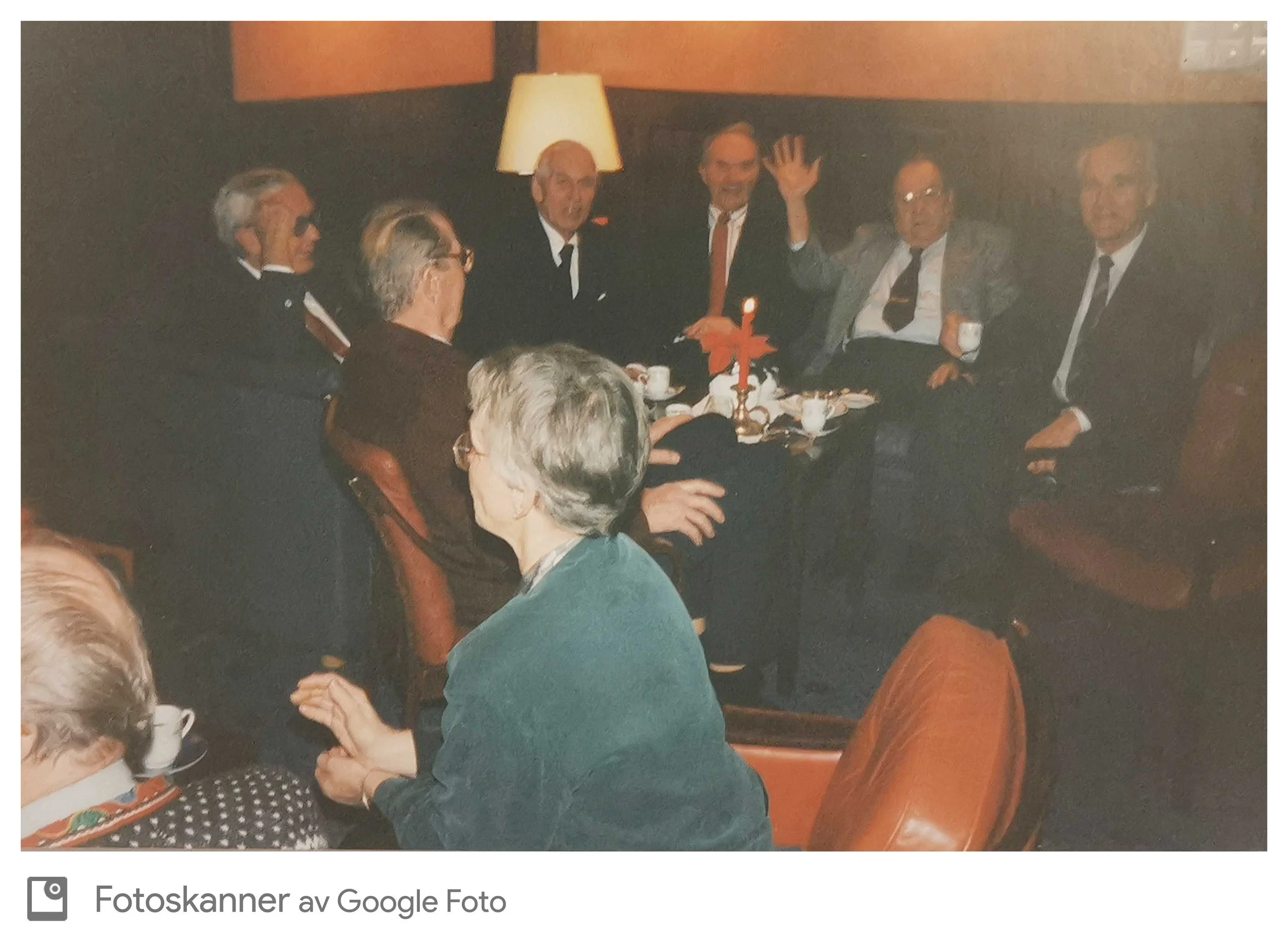 Gruppe mennesker som sitter rundt et bord med kaffekopper og pynt, noe som tyder på en sosial sammenkomst eller feiring.