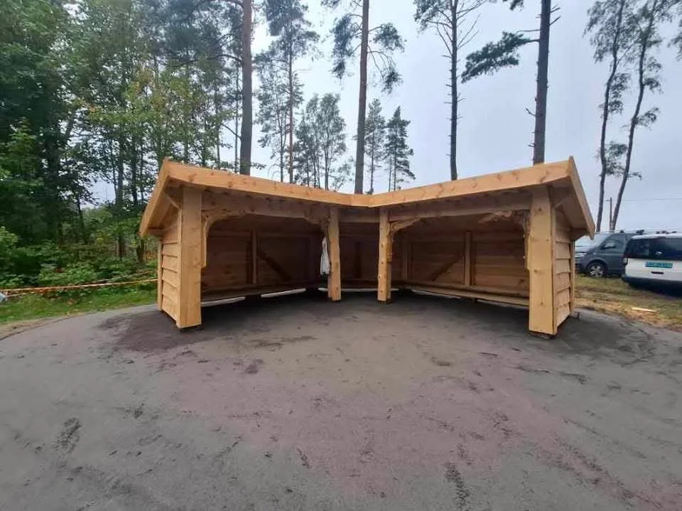 En liten trehytte omgitt av høye grantre ved en innsjø med fjell i bakgrunnen, overflatene er lette å se.