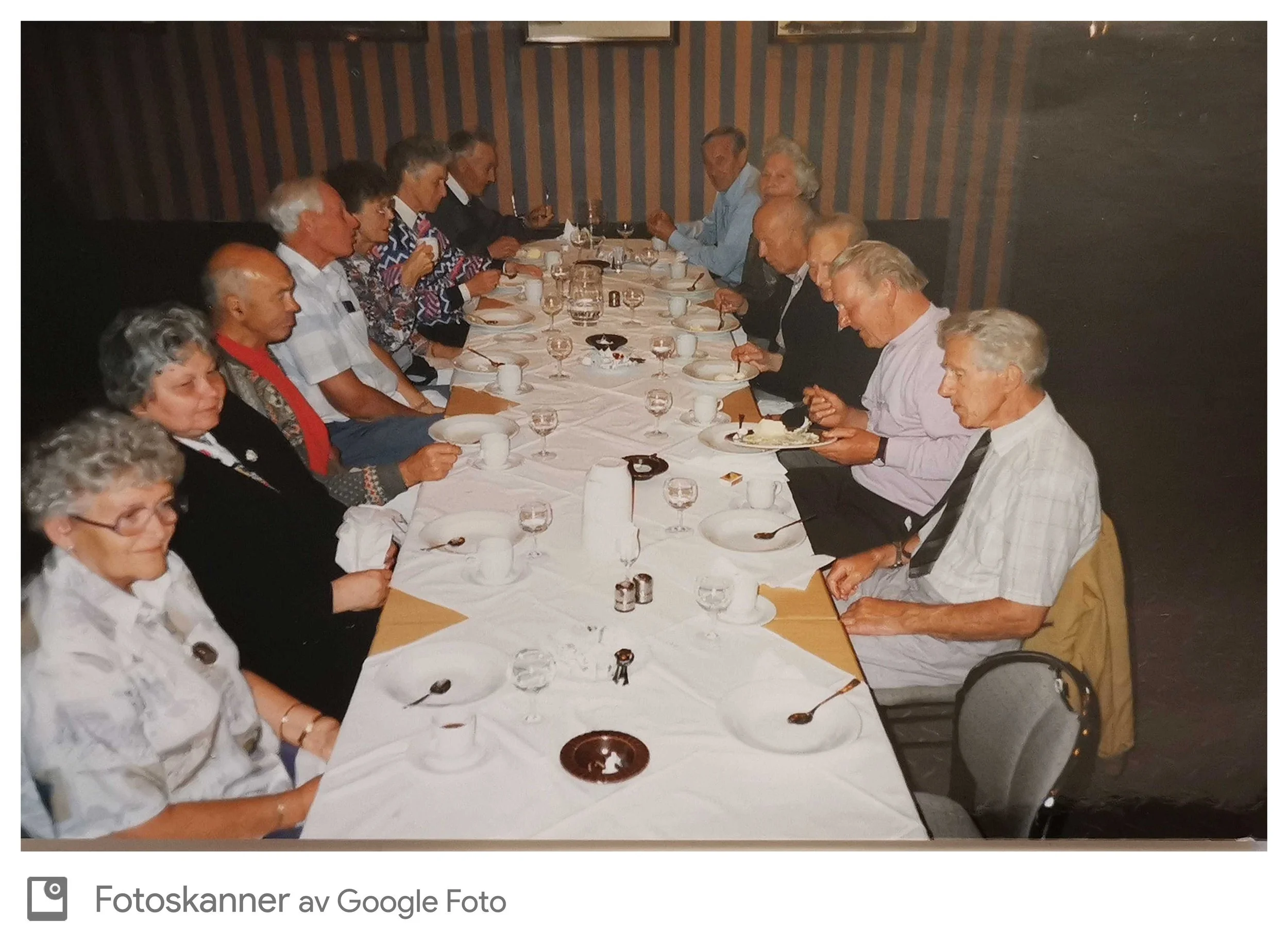 En gruppe eldre mennesker sitter rundt et langbord i et restaurantmiljø.