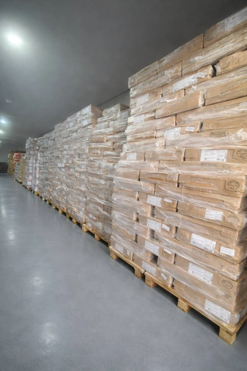 Rows of meats wrapped in plastic on pallets in a warehouse.