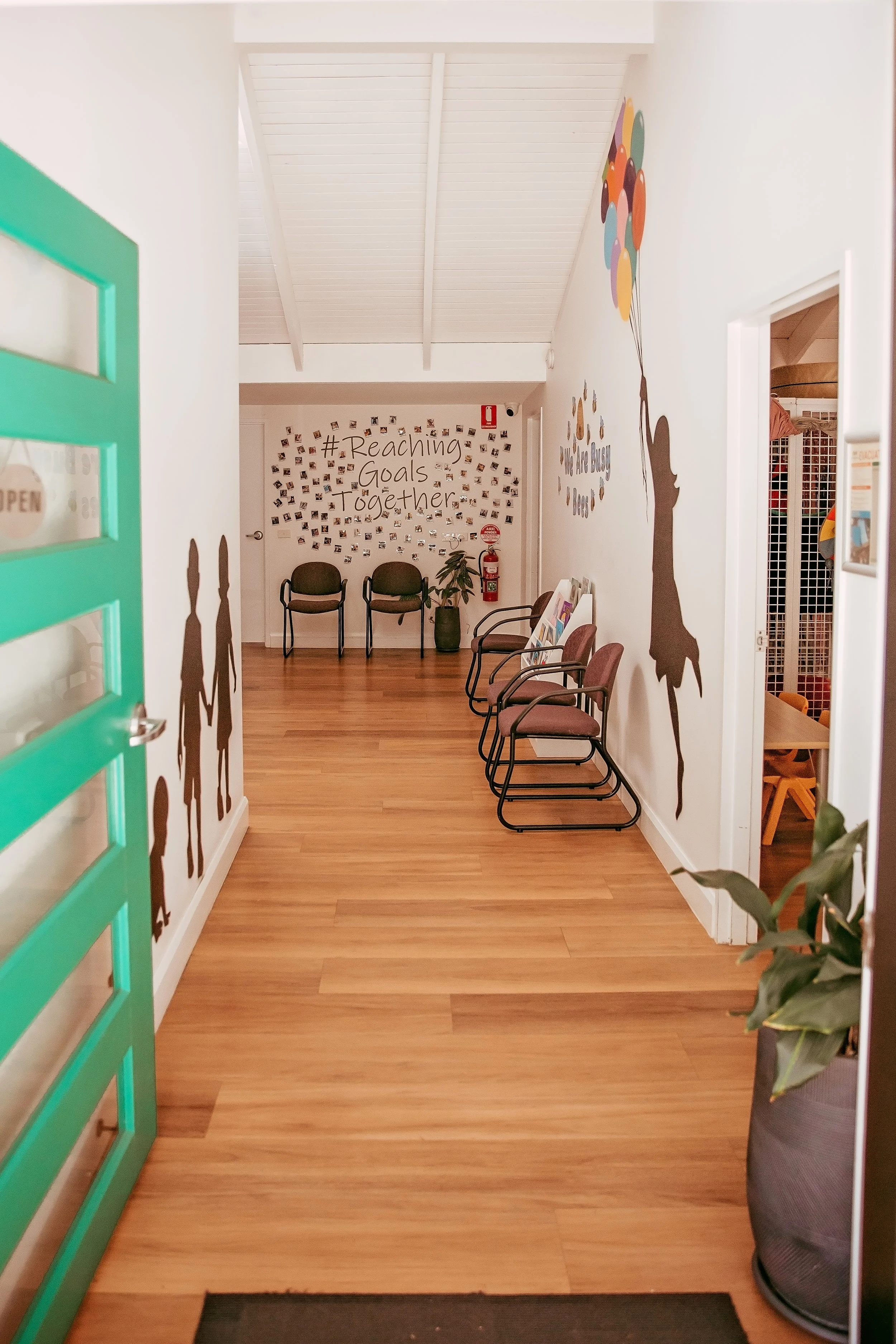 Front access to All Together Therapy, open Green door showing welcome reception space with child friendly wall murals