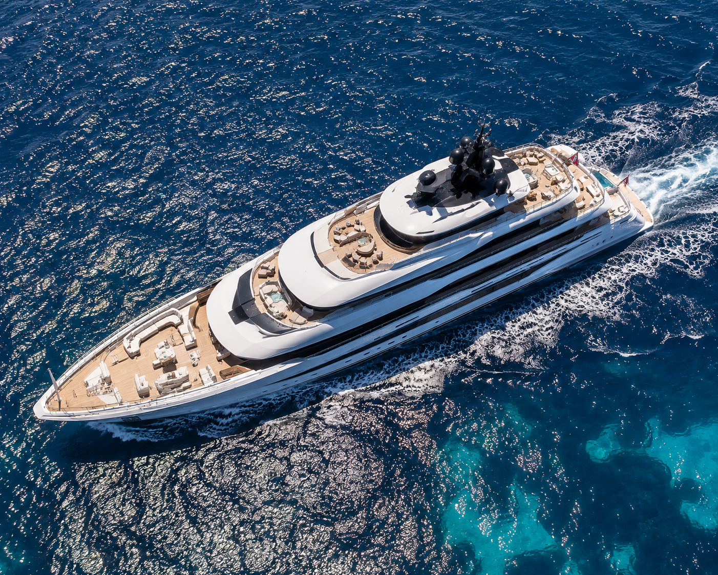 Aerial view of a large luxury yacht sailing in the ocean with blue water and white waves.