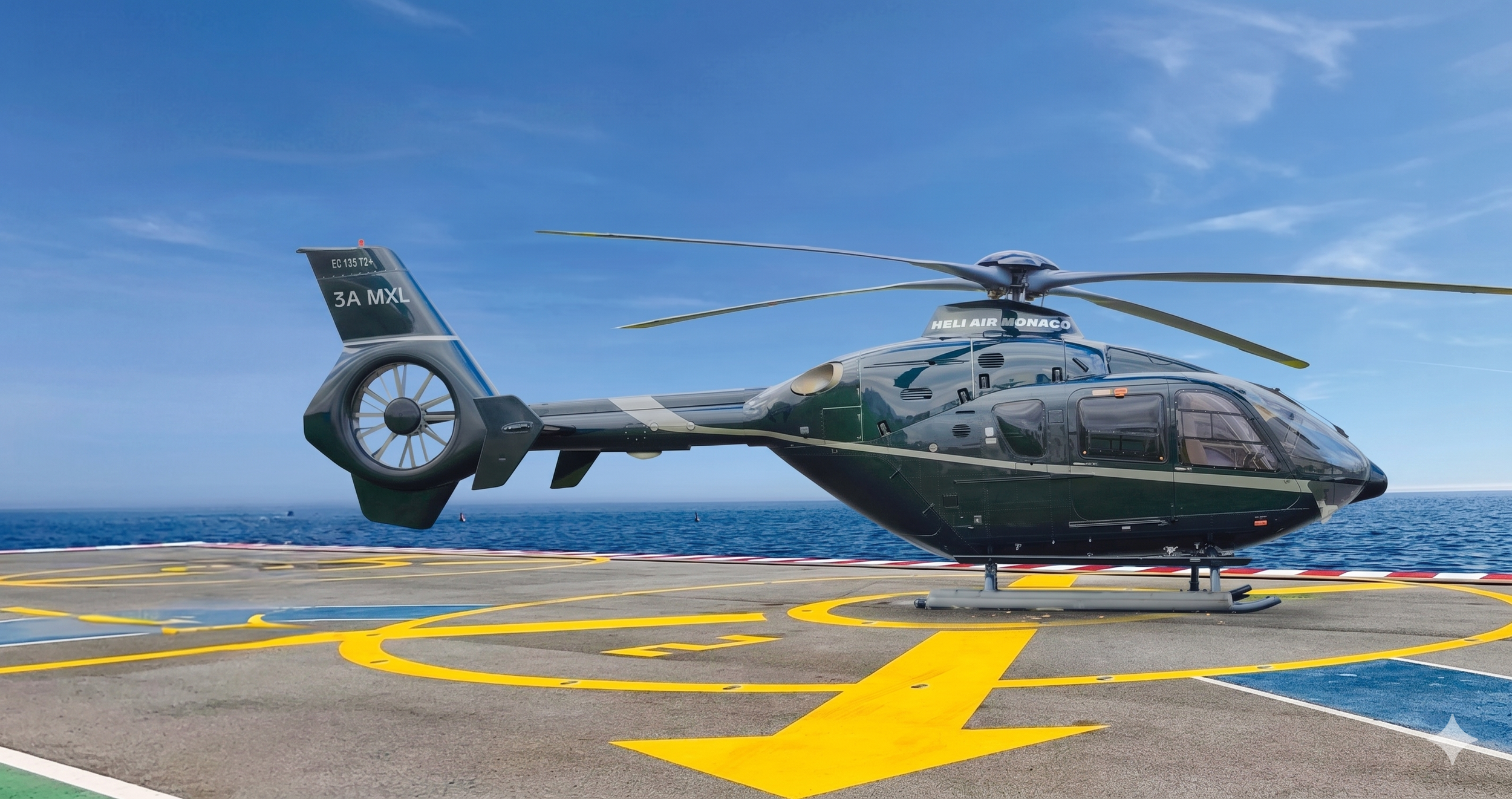 A helicopter on a helipad with a yellow circular marking, near the ocean under a blue sky with some clouds.