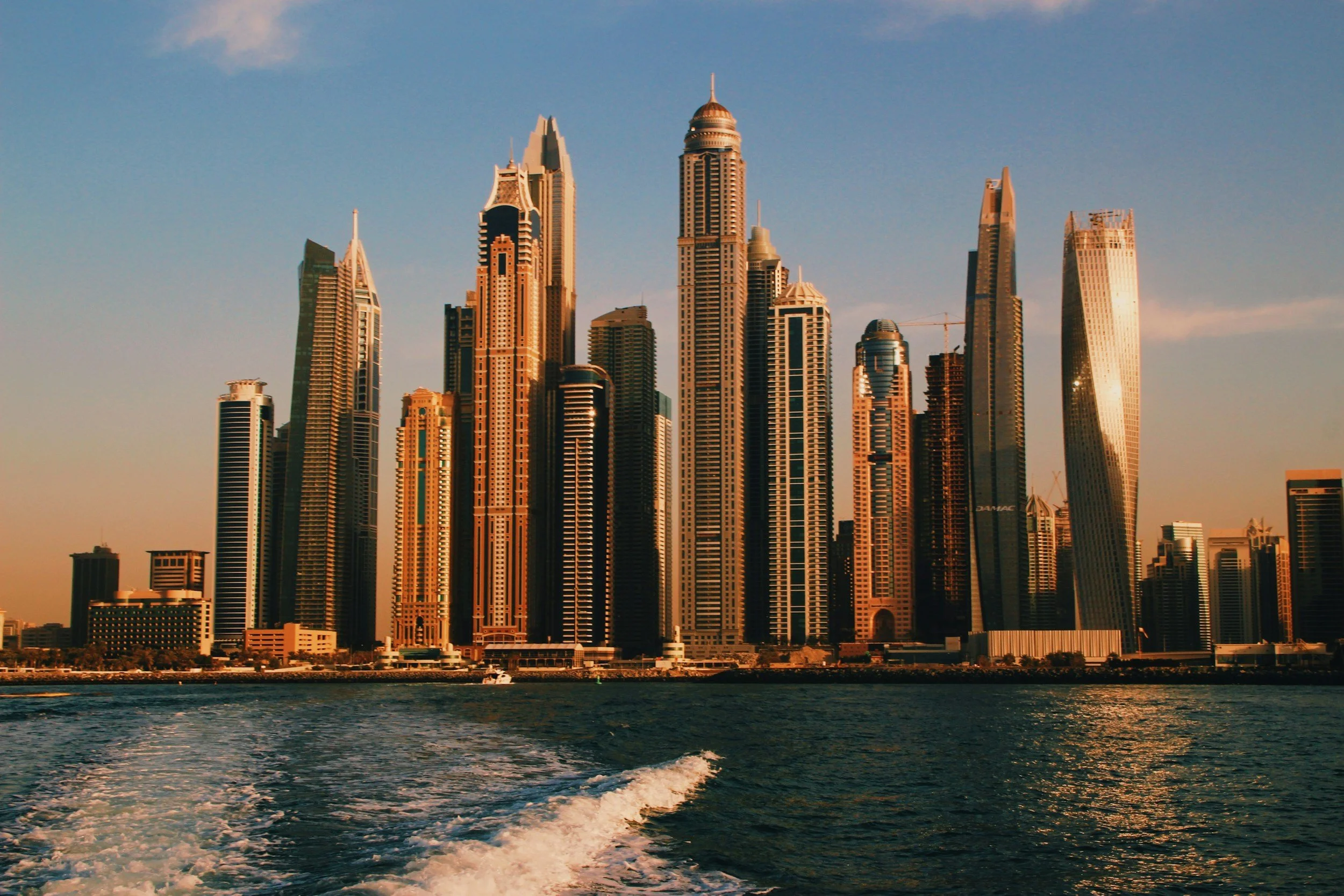 City skyline with tall skyscrapers seen from water during sunset.