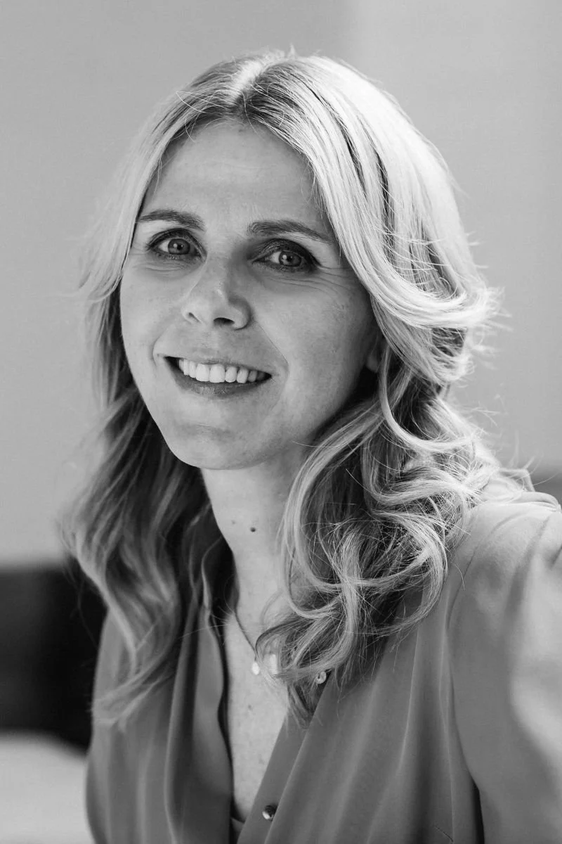 Black and white portrait of a woman with wavy, shoulder-length hair smiling at the camera.