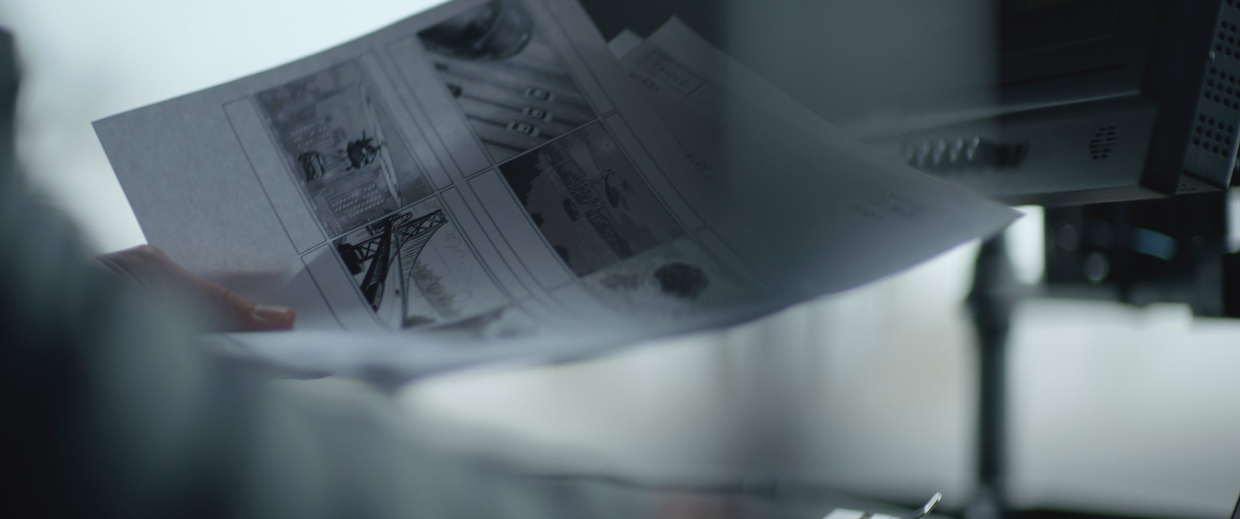 Close-up of a person using a machine to print or process a sheet of paper with black-and-white illustrations.