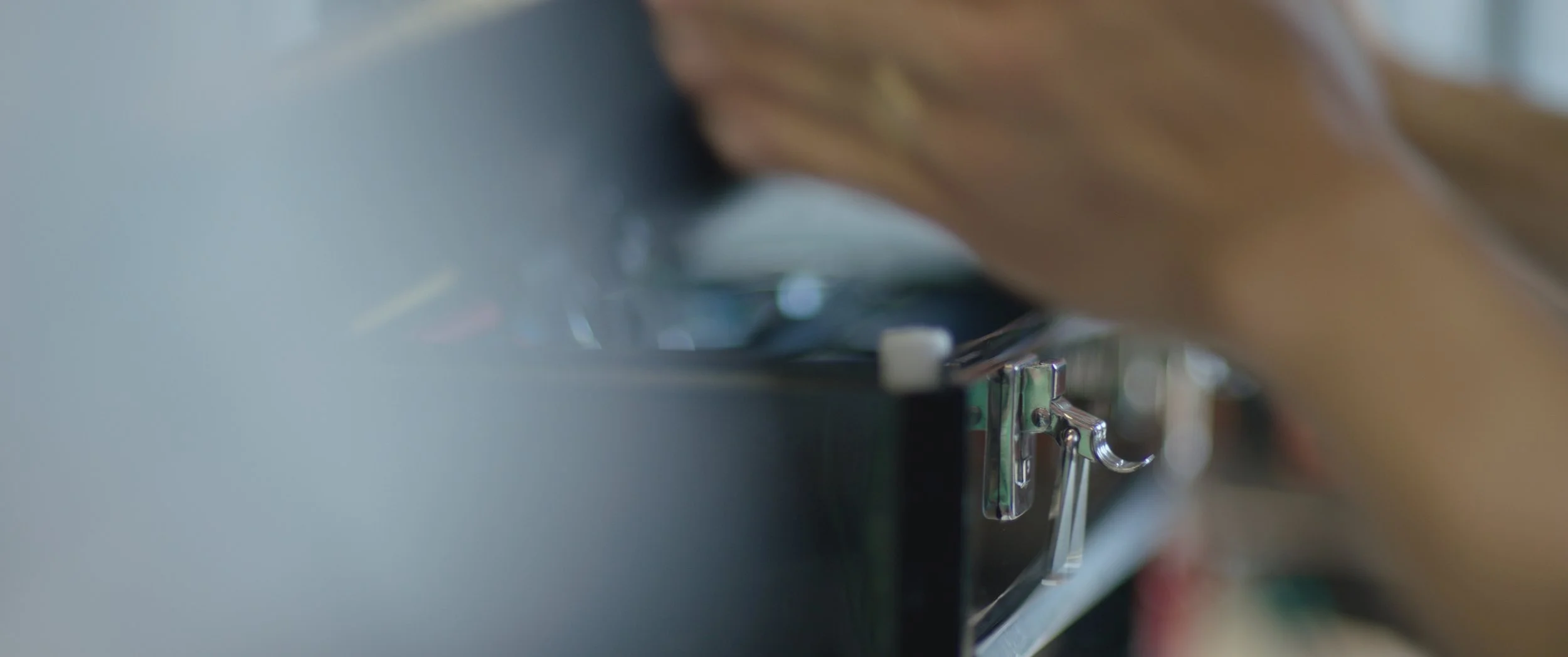 Close-up of a person's hand operating a sewing machine.