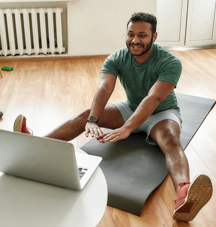Client joining an online physiotherapy consultation from home, connected to NRG Sports Therapy via video call on a laptop.