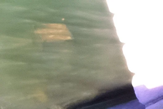 Close-up of a boat's edge on water with reflections and ripples.