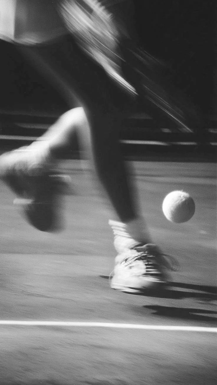 A person playing tennis, running after a tennis ball on the court.