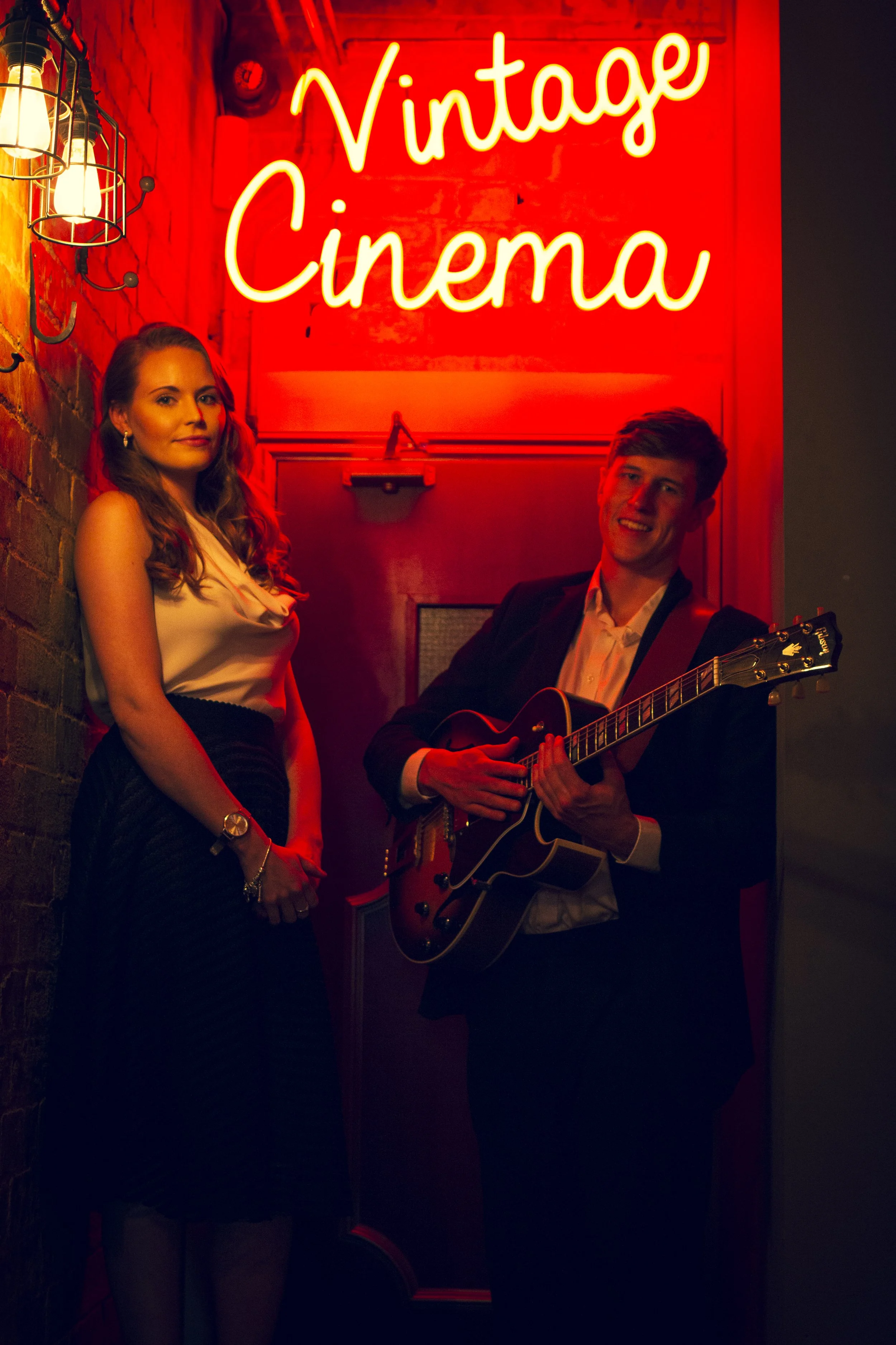 Kay from Sing with Kay with guitarist standing outside a vintage cinema in Leicester promoting Kay Acoustic acoustic duo for live music, weddings, and events