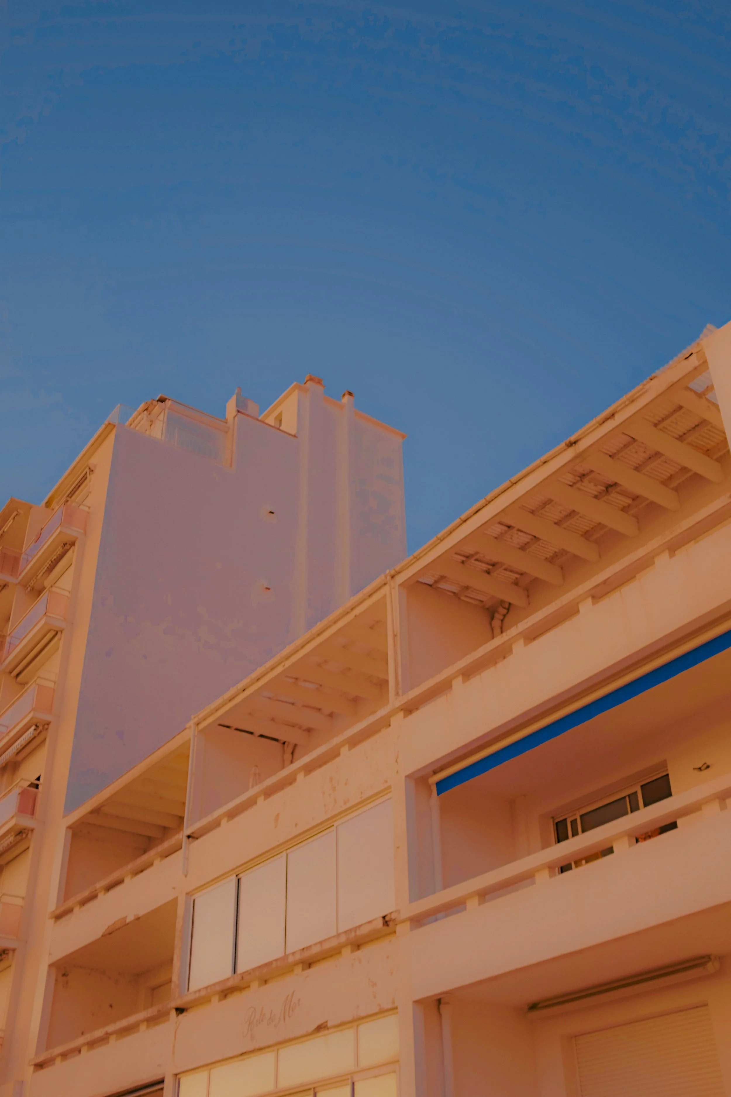 Bâtiment résidentiel avec plusieurs balcons et un ciel bleu en arrière-plan.