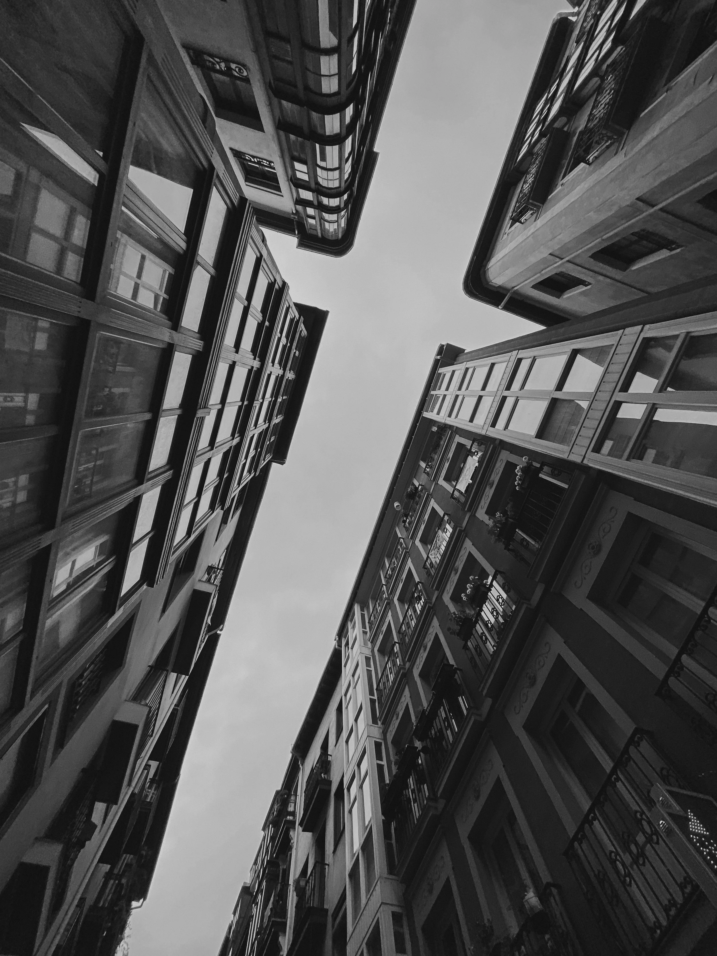 Vue en plongée d'immeubles résidentiels modernes et anciens, avec des balcons en fer forgé, sous un ciel clair.
