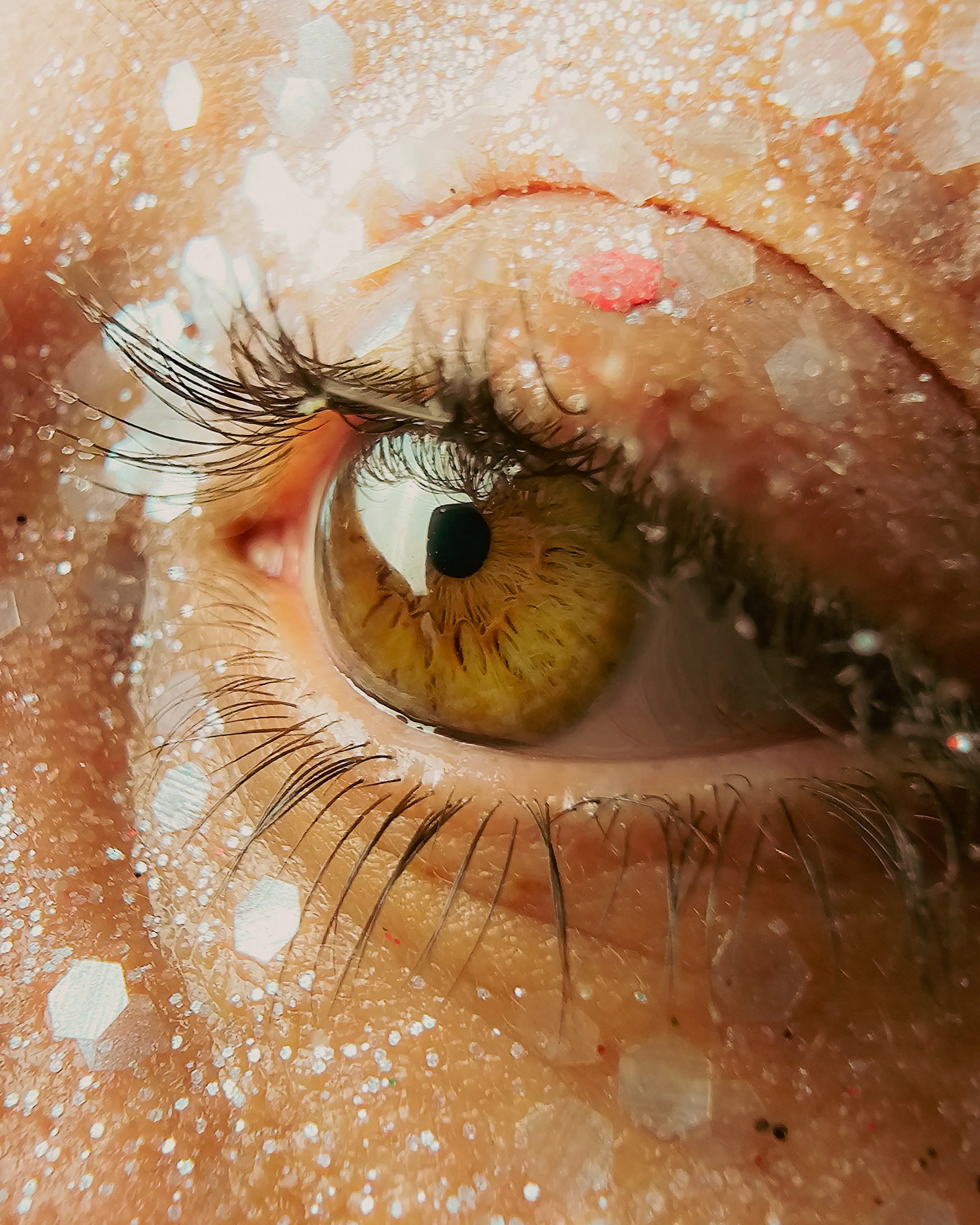 Gros plan d'un œil humain avec des détails de la paupière, des cils, de la pupille et de l'iris, entouré de peau avec des reflets de lumière.