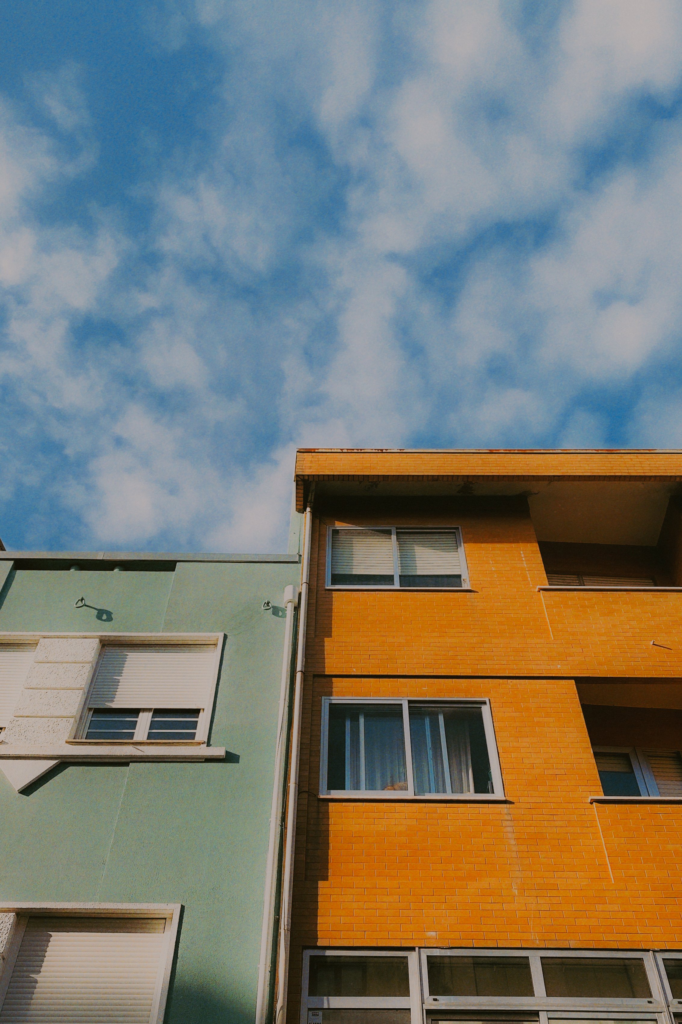 Façades de deux immeubles dans un ciel bleu avec quelques nuages.