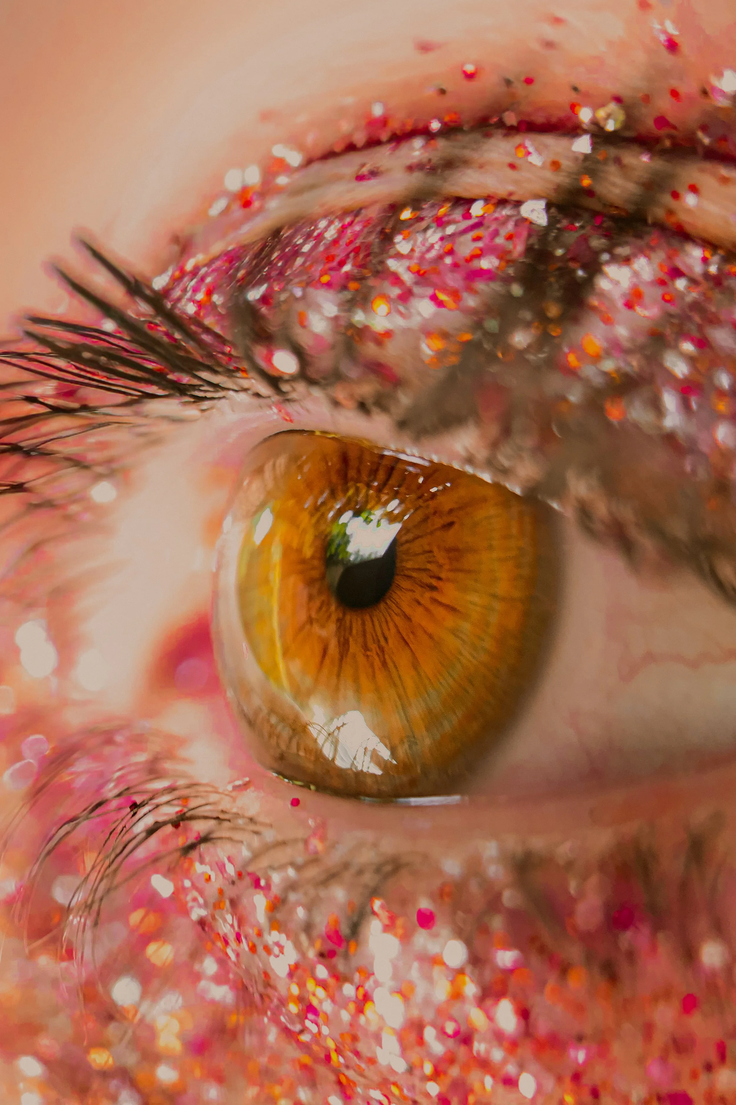 Zoom sur un œil avec des cils longs, mascara et maquillage avec des paillettes roses et rouges.