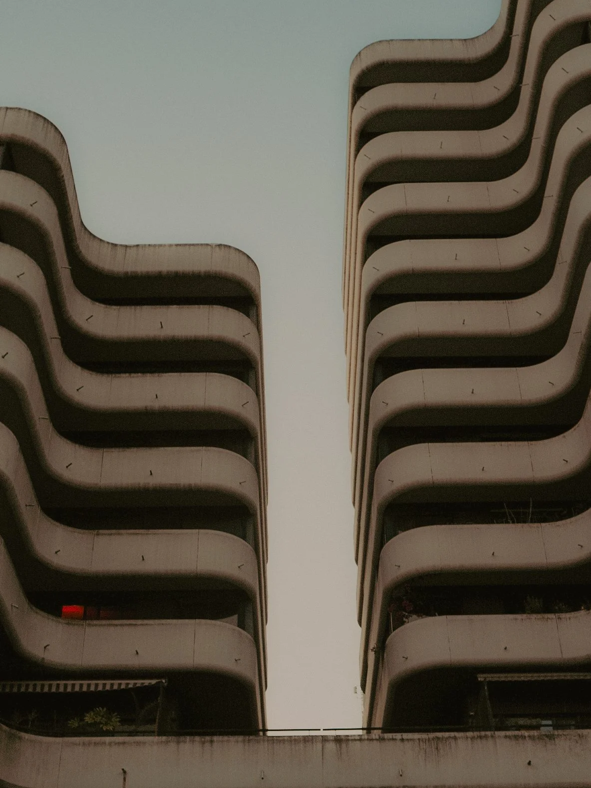 Deux grands immeubles modernes avec des balcons courbés, vus de bas en haut.