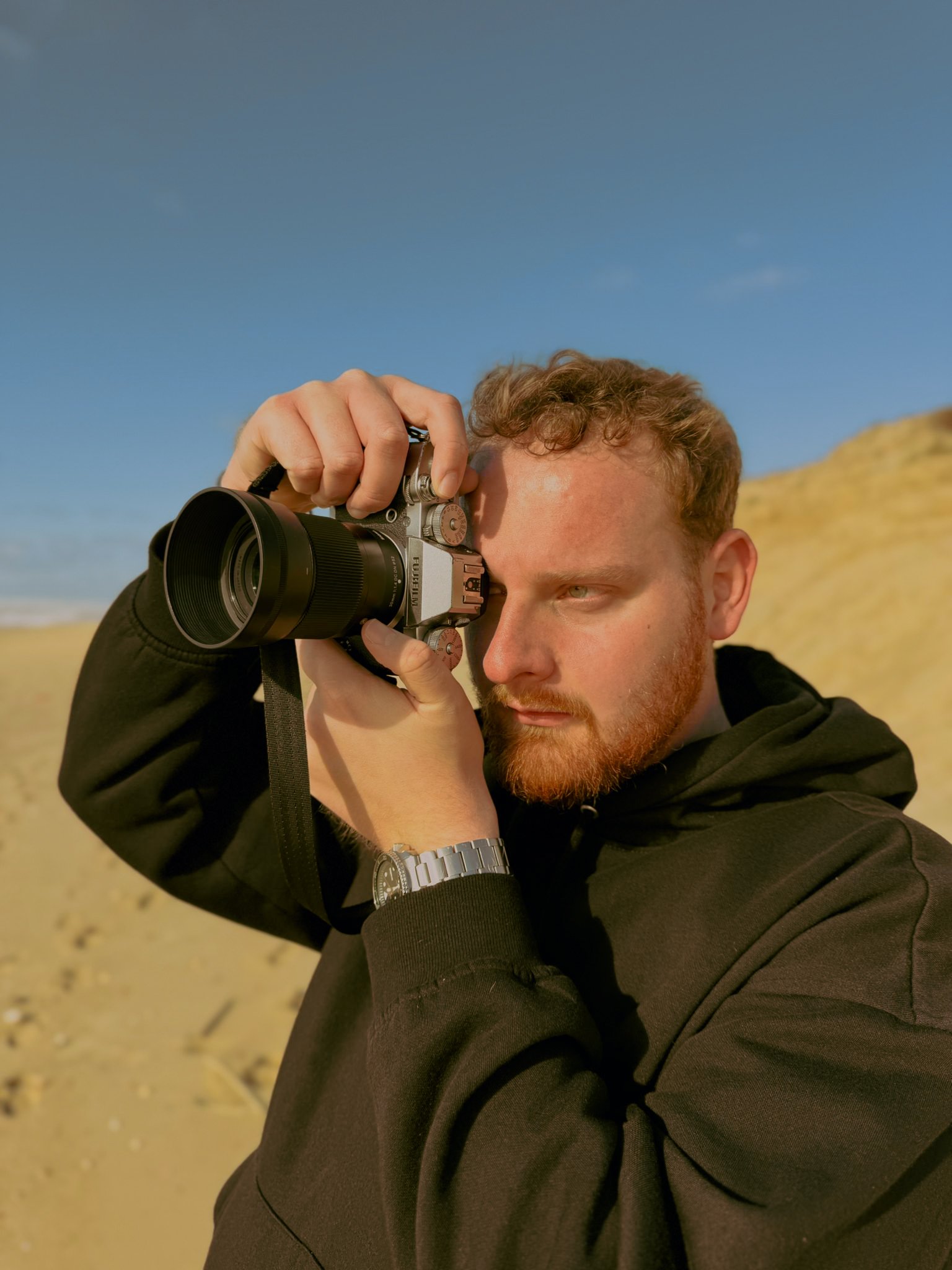 Homme prenant une photo avec un appareil photo numérique sur une plage ensoleillée