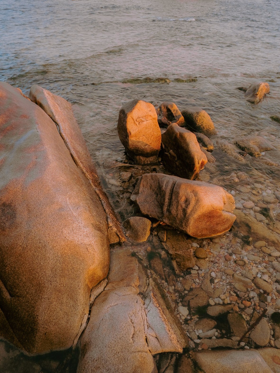 Rochers au bord de l'eau, avec la mer en arrière-plan, lors du coucher du soleil.