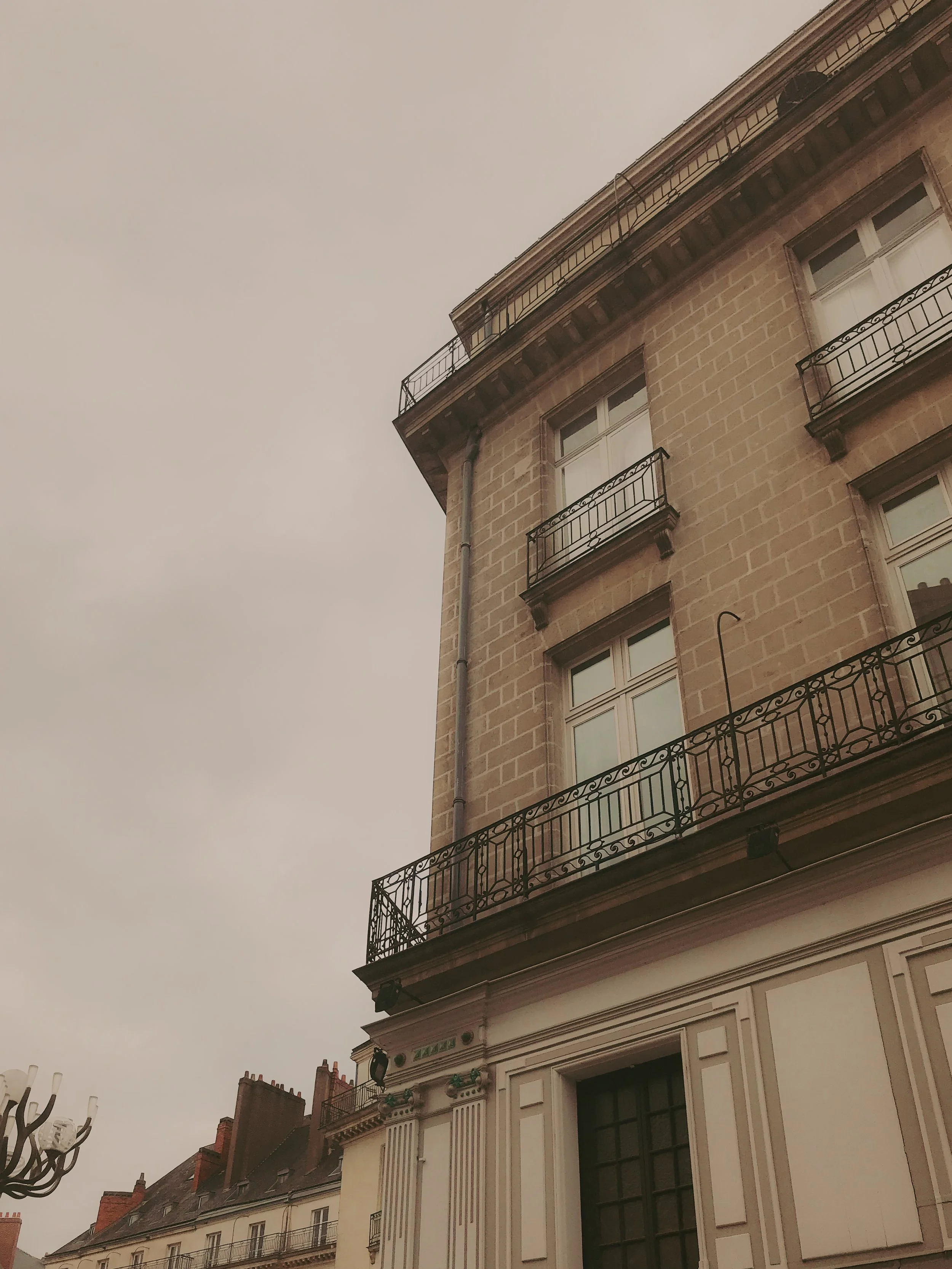 Façade d'un bâtiment en pierre avec balcons en fer forgé et fenêtres.