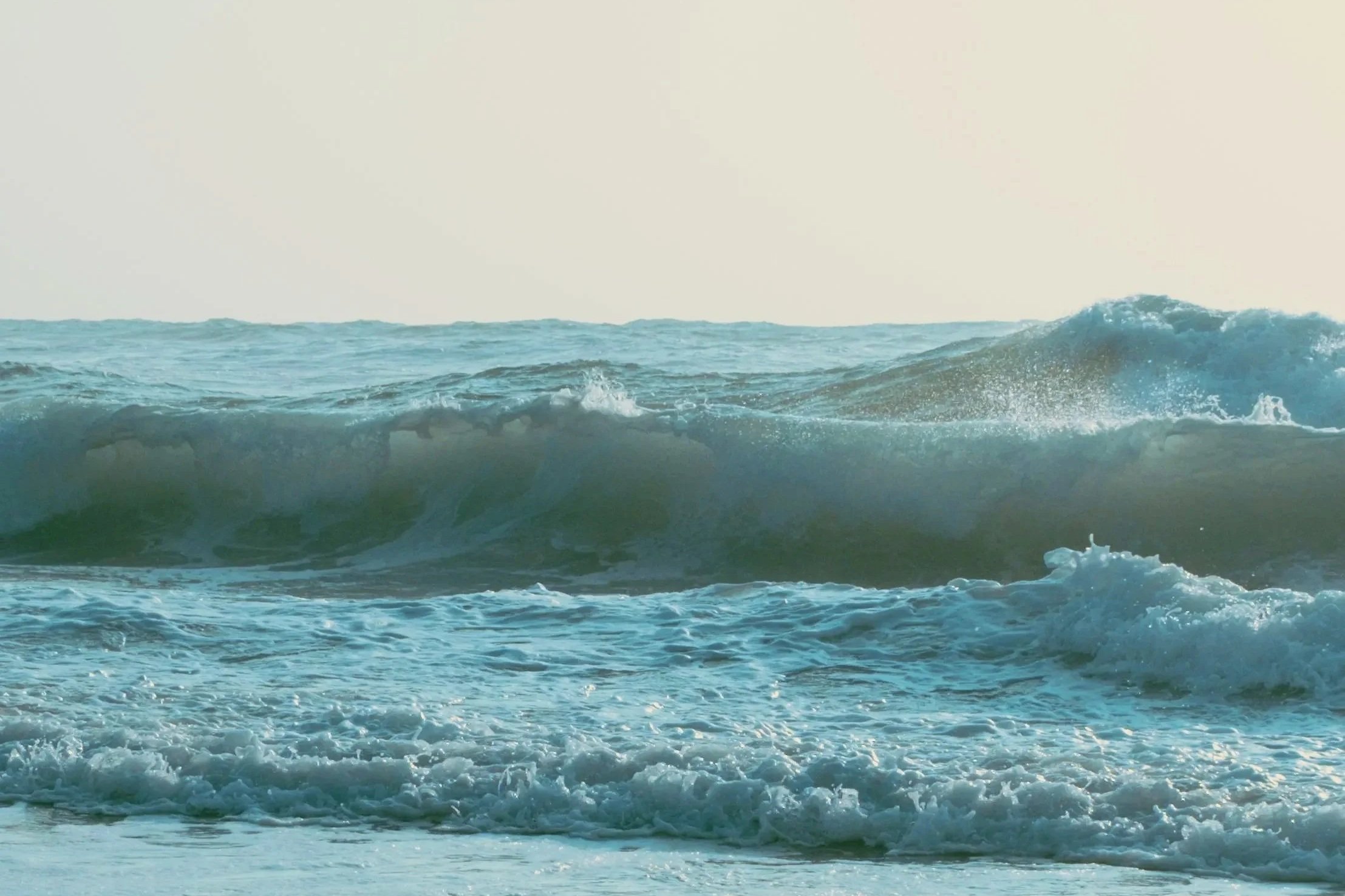 Vagues de mer s'écrasant sur la plage sous un ciel clair.