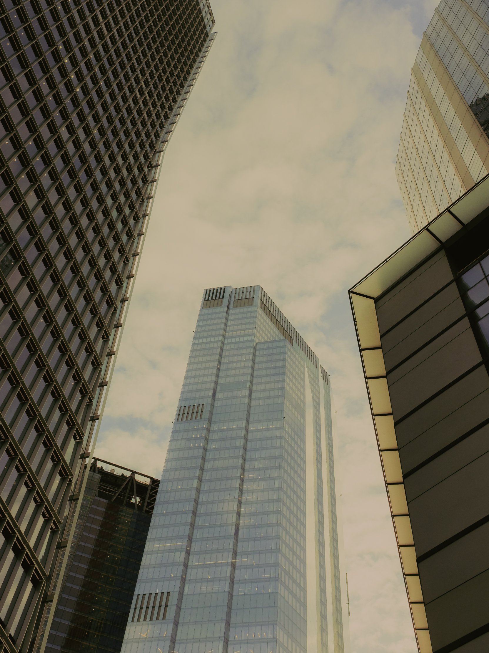 Prise de vue en contre-plongée de plusieurs gratte-ciels modernes en verre dans un ciel nuageux.