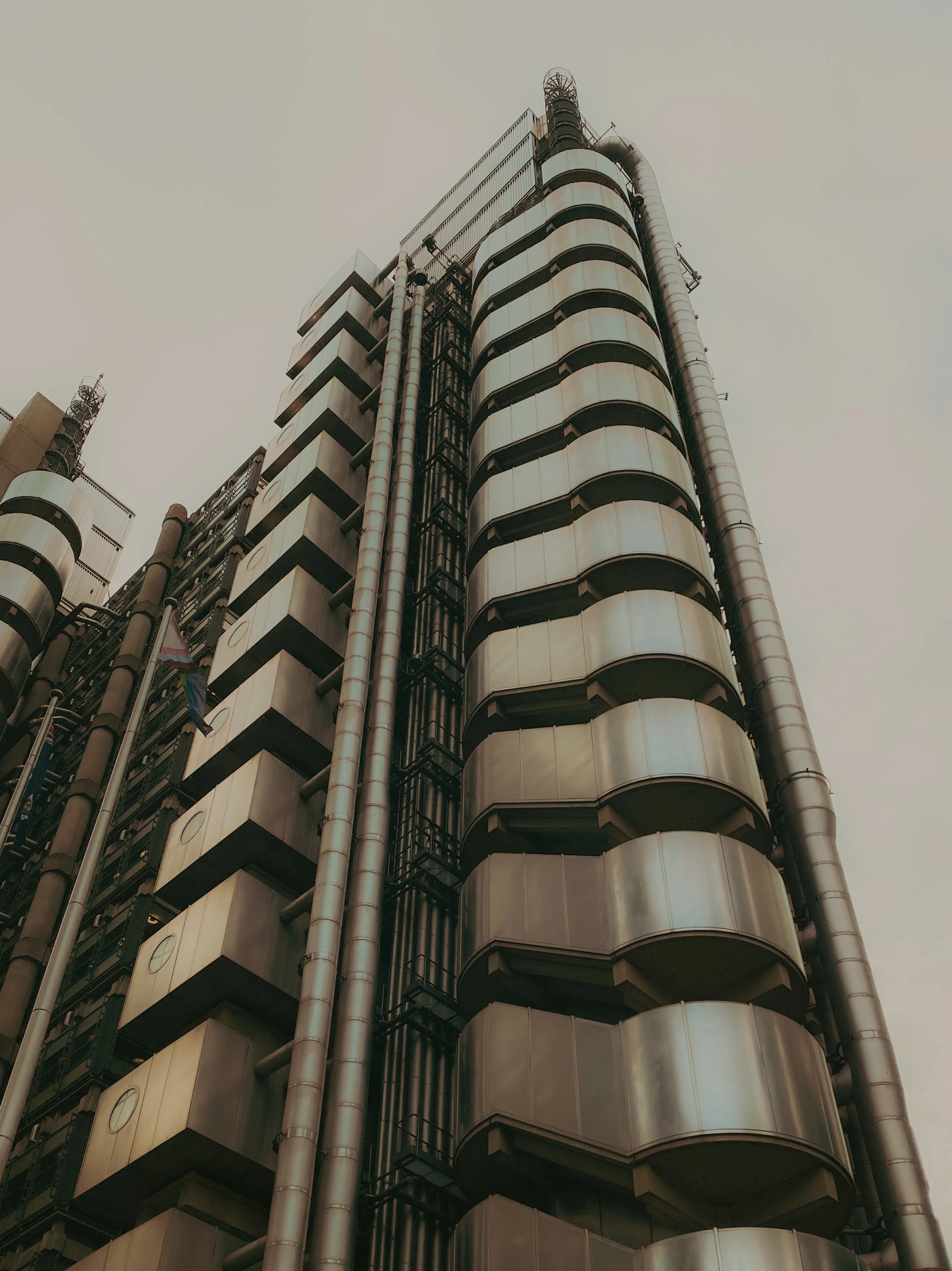 Gratte-ciel moderne avec des balcons en forme d'arc et des tuyaux métalliques visibles à l'extérieur, vue de bas en haut.