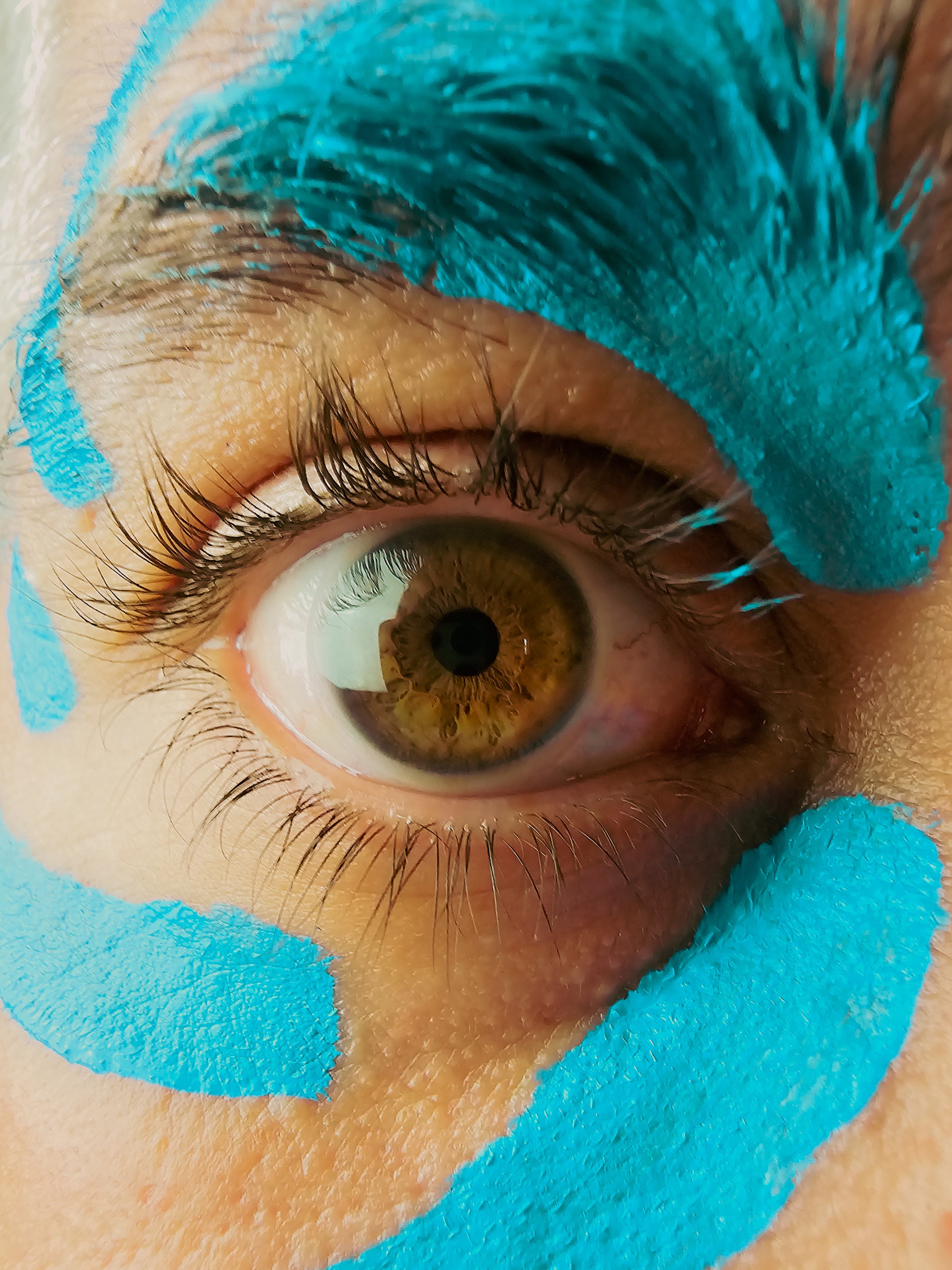 Un œil humain avec des marques de peinture bleue autour de l'œil.