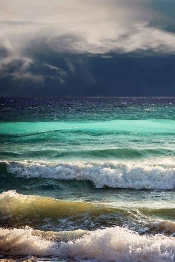 Vagues animées en mer sous un ciel nuageux, couleurs turquoise et bleu profond.
