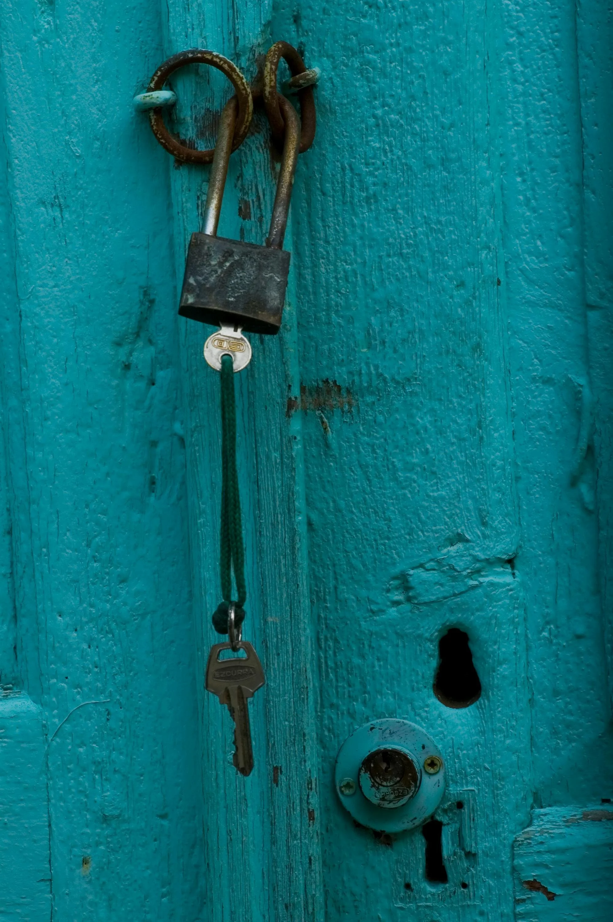 keys dangling from blue door on rusty lock representing knowing differences