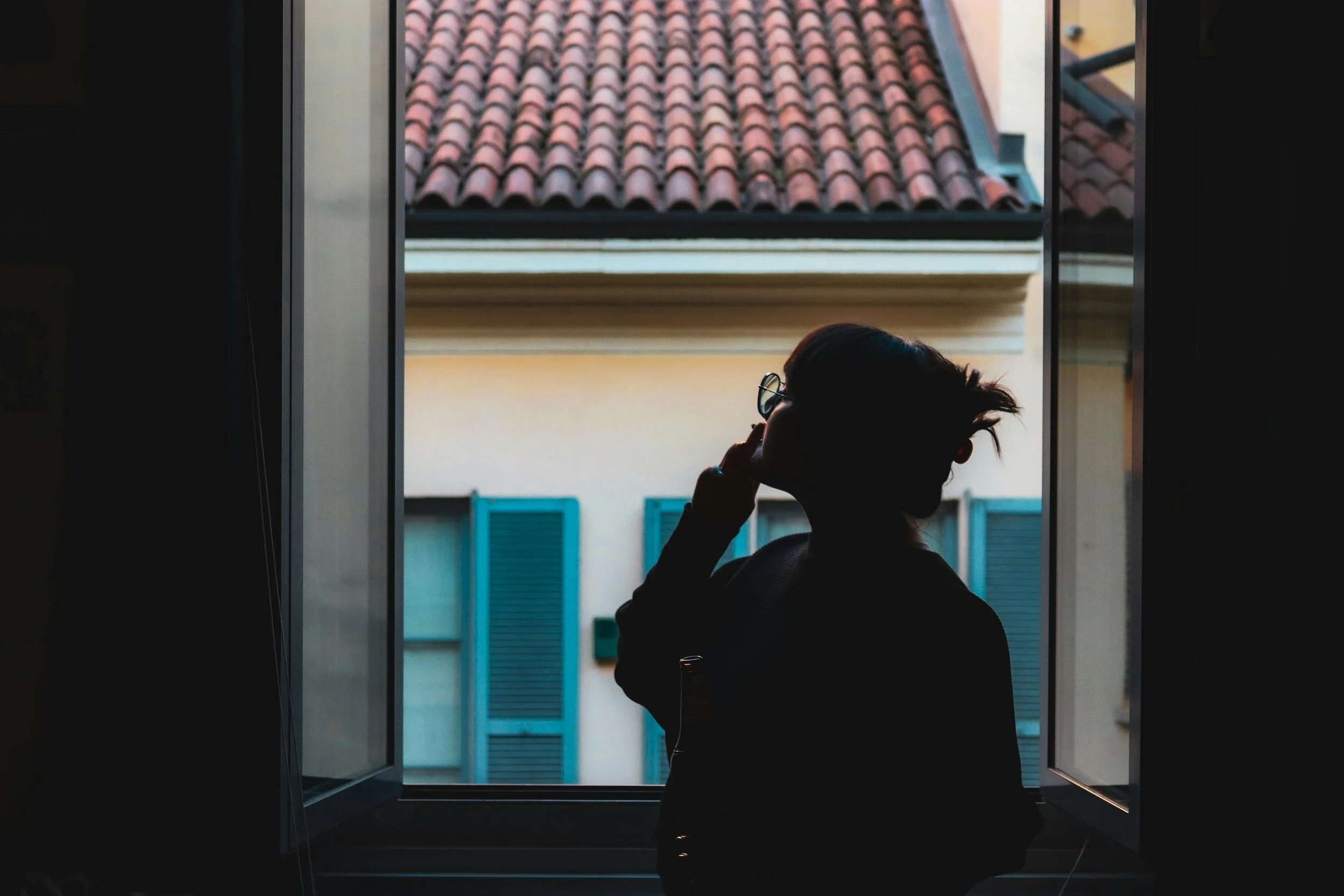 Thoughtful woman sitting near a window in soft natural light.