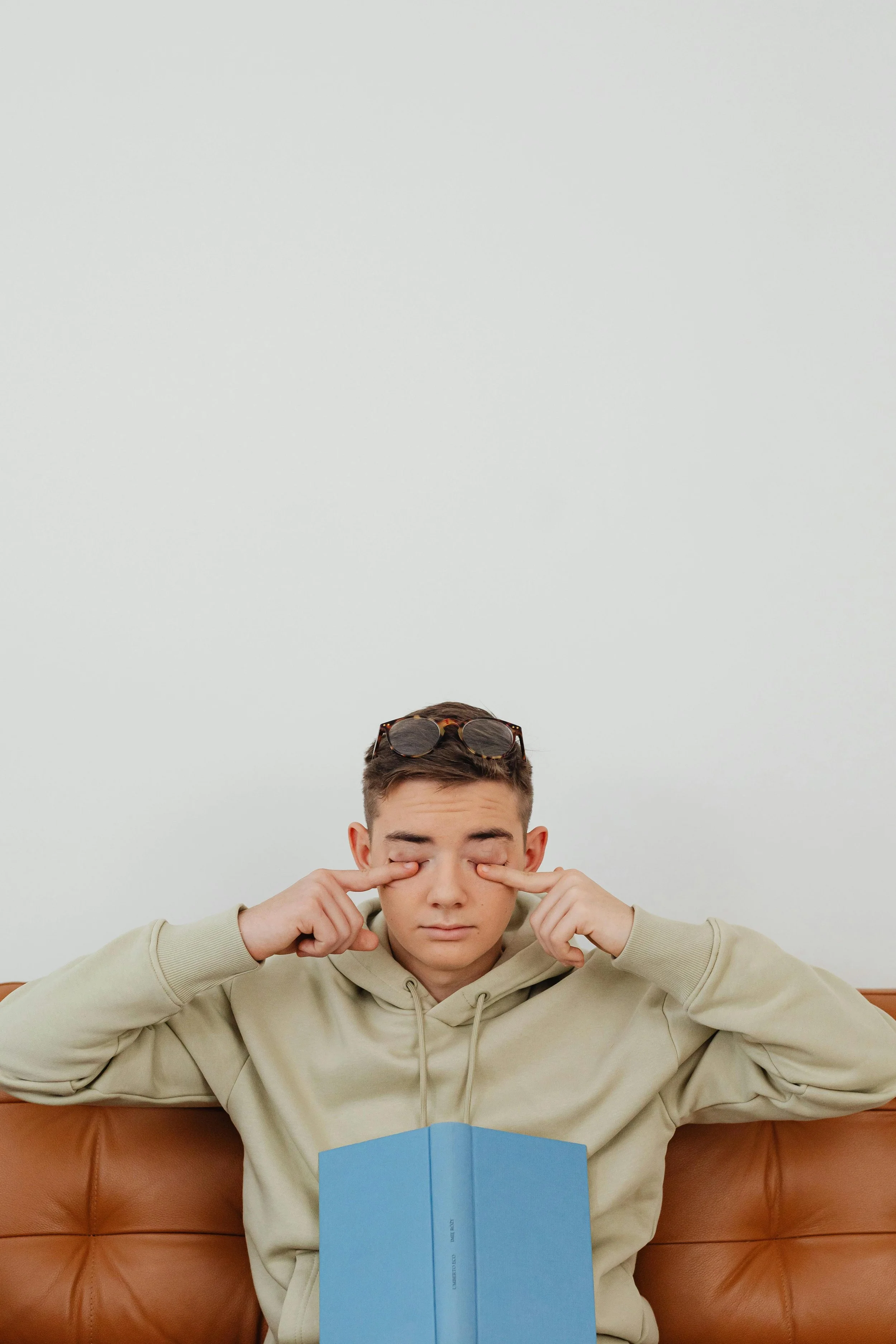 man sitting on couch with book trying to mind read because he is overthinking and experiencing feelings of anxiety
