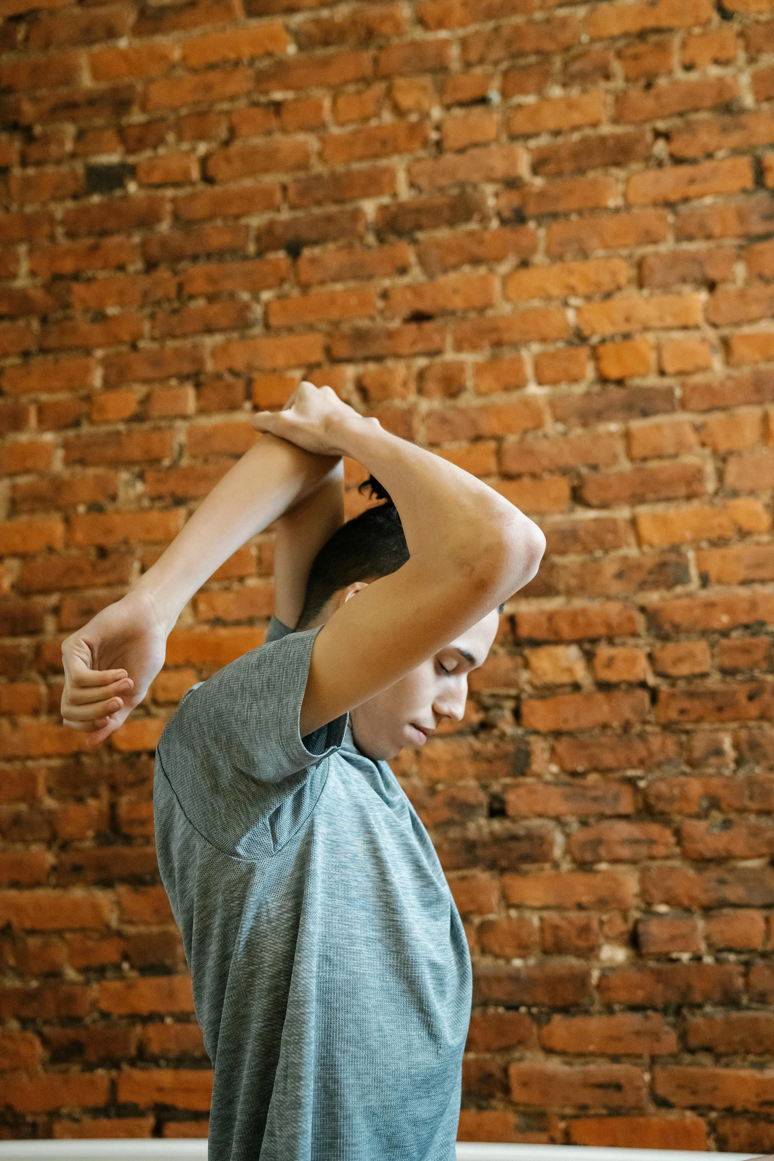 man stretching with eyes closed next to brick wall - body signals and mindfulness feeling and senses
