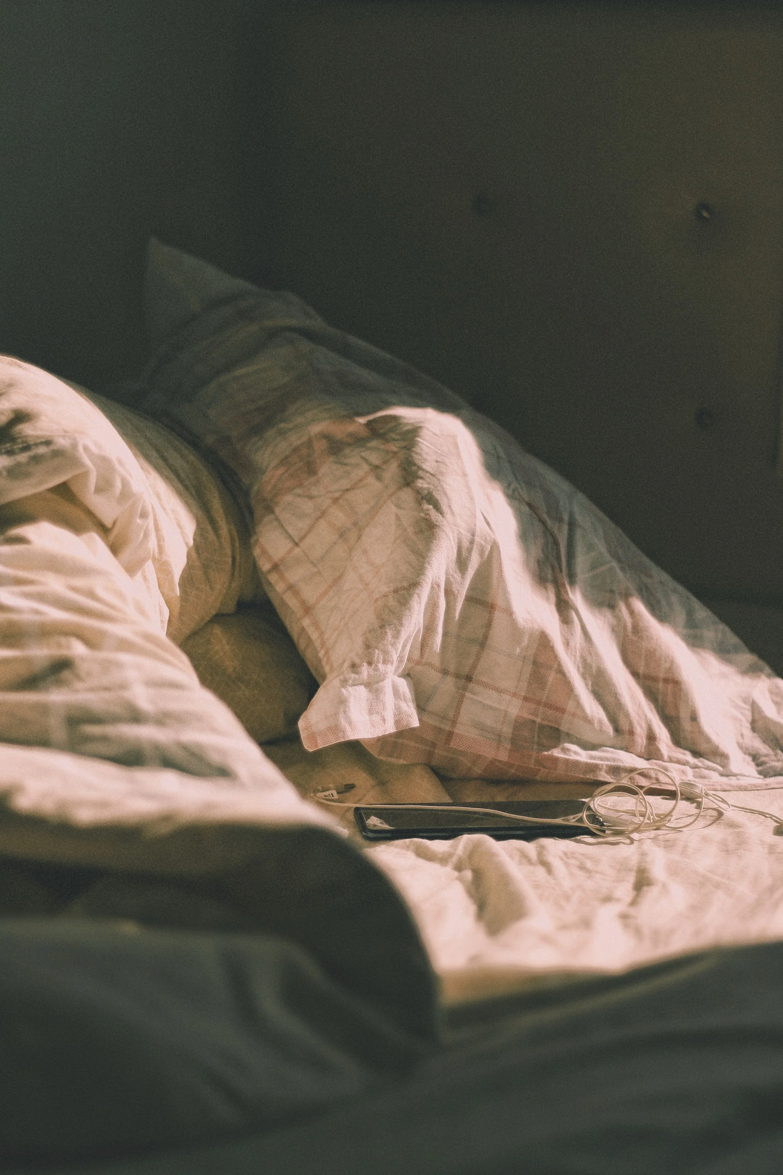 phone on bed by pillows with wires and chords