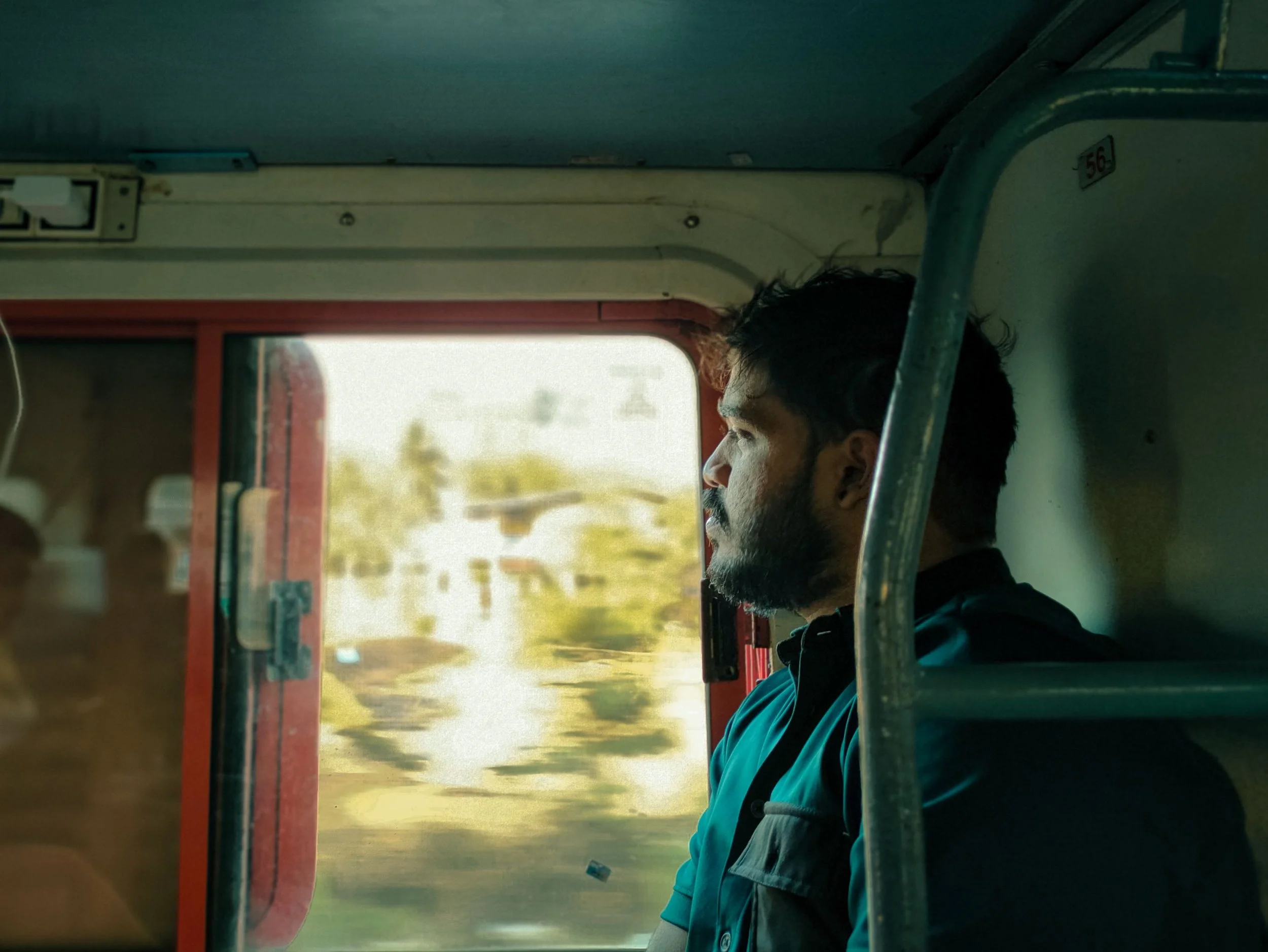 man with beard sitting alone on train driving past nature contemplating life and thinking about his problems