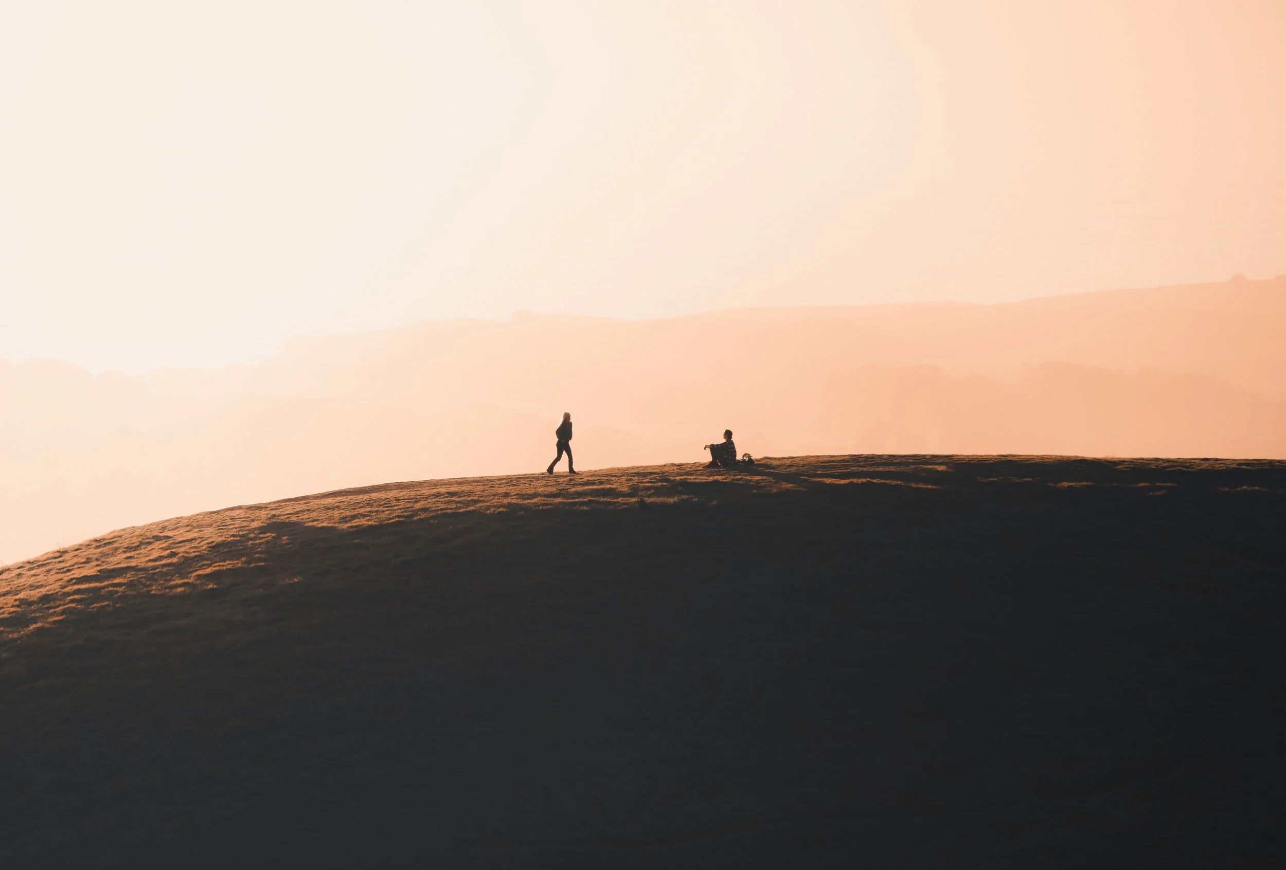 two people on mountain with backdrop of sunrise - in serene, calm, beautiful nature