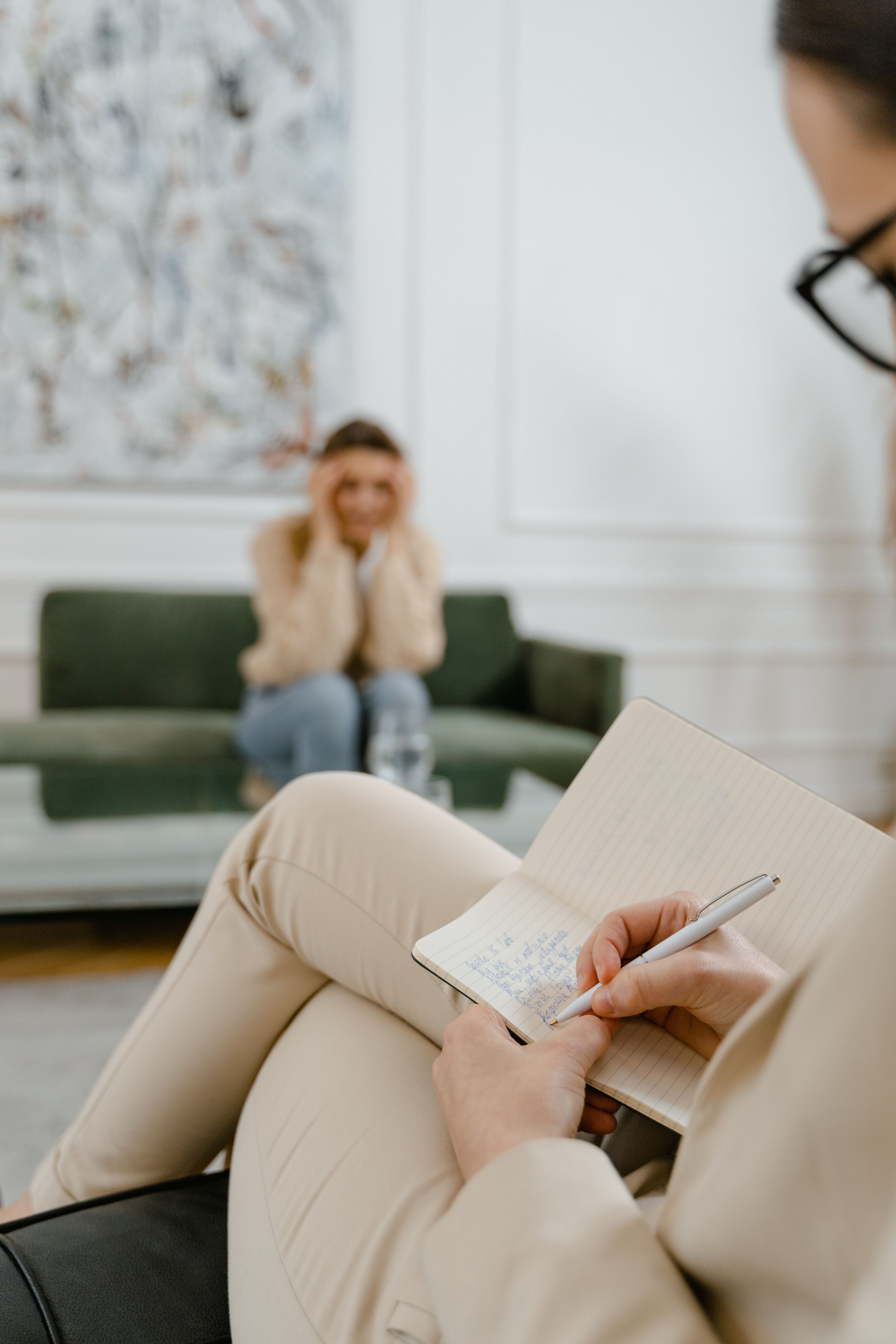 therapist talking with concerned female client and taking notes in her book about disposition and diagnoses and psychology