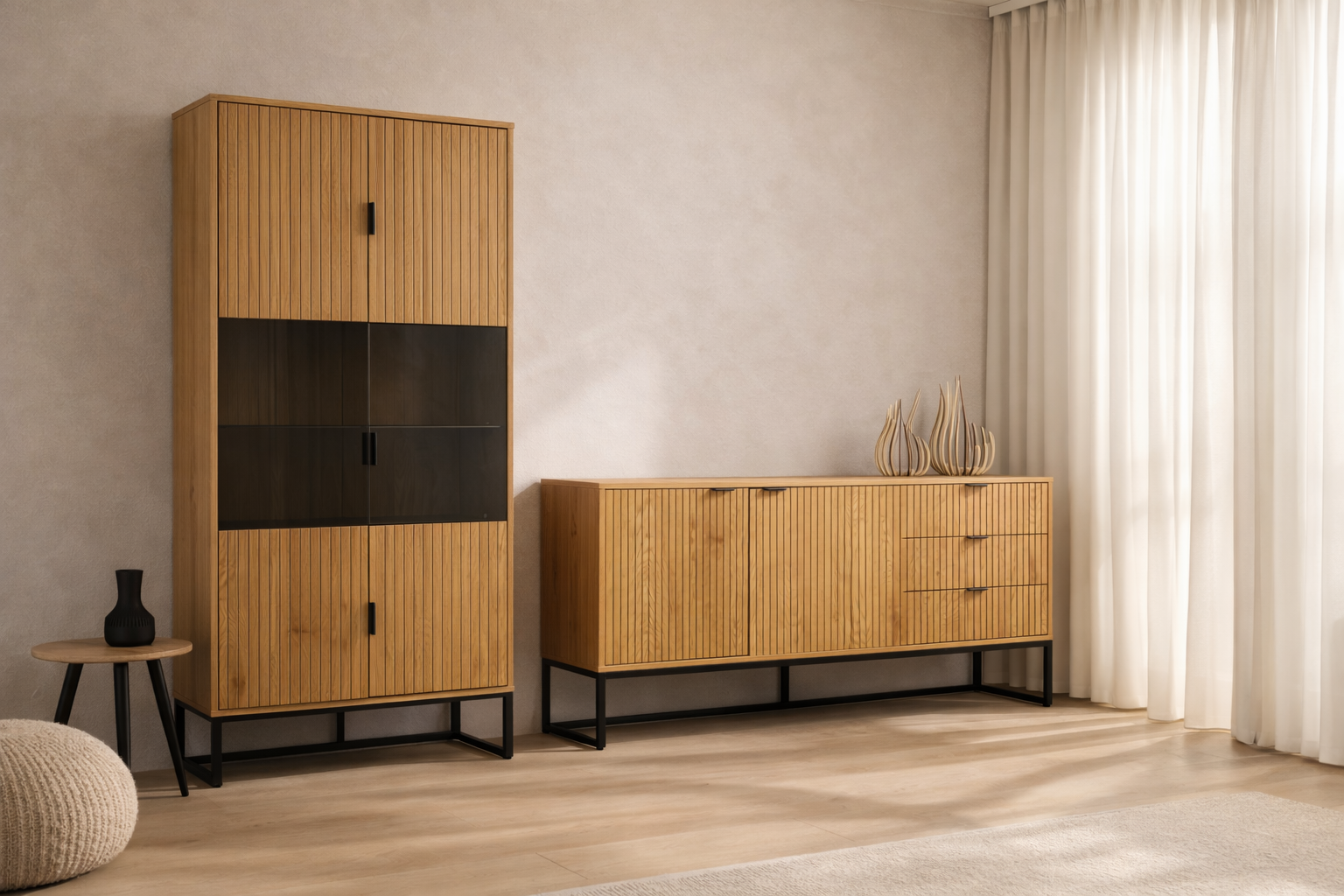 Muebles de madera en una sala con cortinas blancas, un armario alto con puertas de madera y cristal oscuro, un mueble bajo con decoraciones de cerámica y una pequeña mesa con una jarra negra.