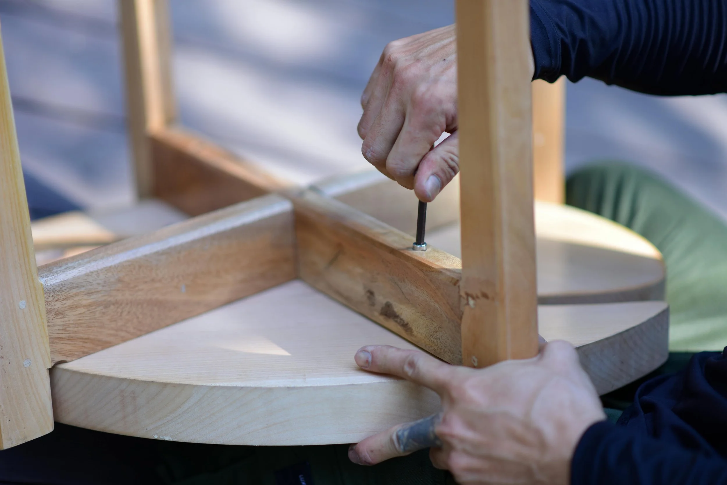 Persona ensamblando una estructura de madera usando un destornillador en un trabajo de carpintería.
