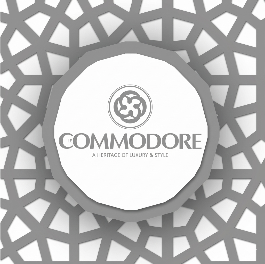 A decorative box with a geometric pattern on the lid, featuring a logo and the text 'Le Commodore: A Heritage of Luxury & Style'.