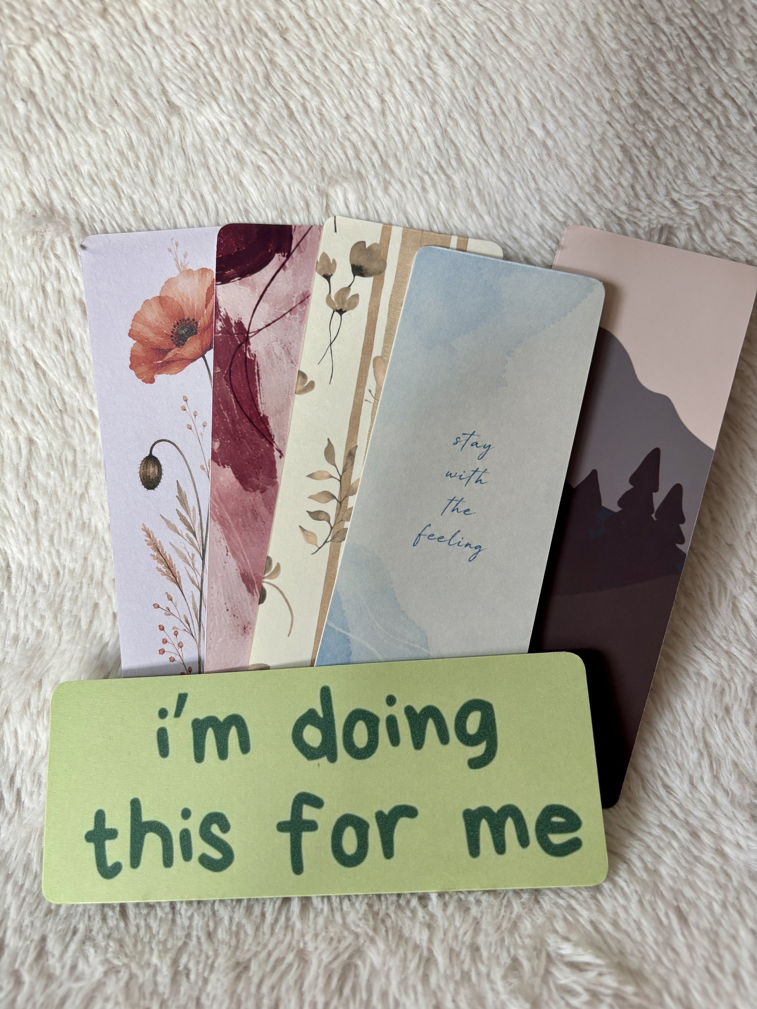 Set of six unique bookmarks with floral, abstract and quote designs arranged on a soft neutral background.