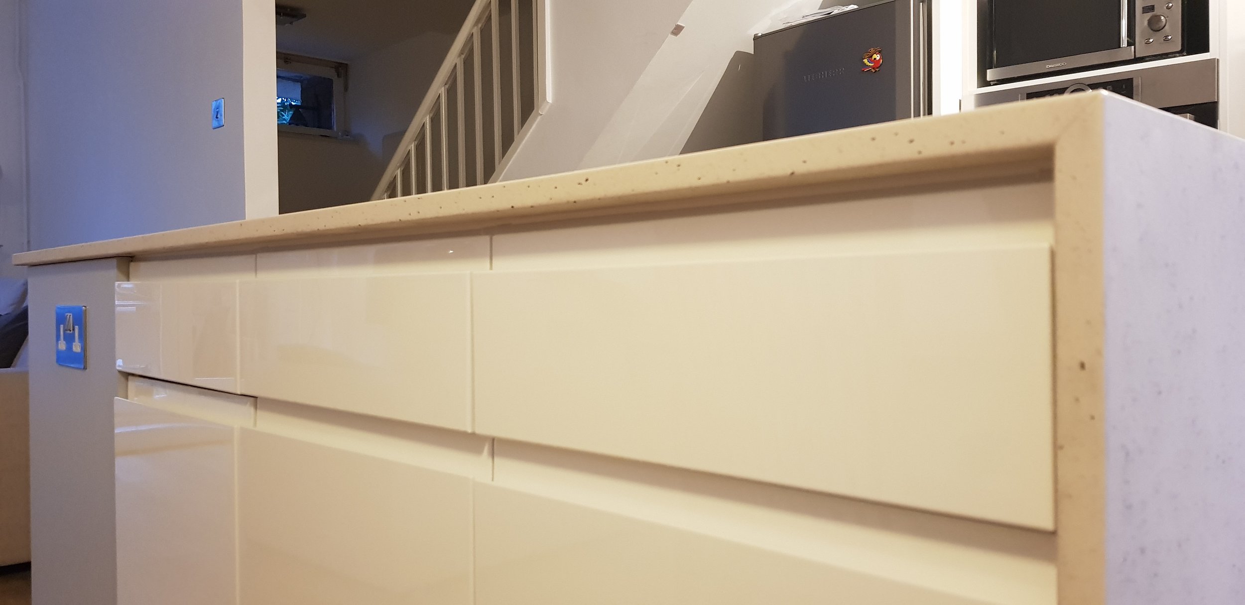 Close-up of new cream-colored kitchen cabinetry with a smooth granite countertop, following a kitchen redesign and open plan renovation.