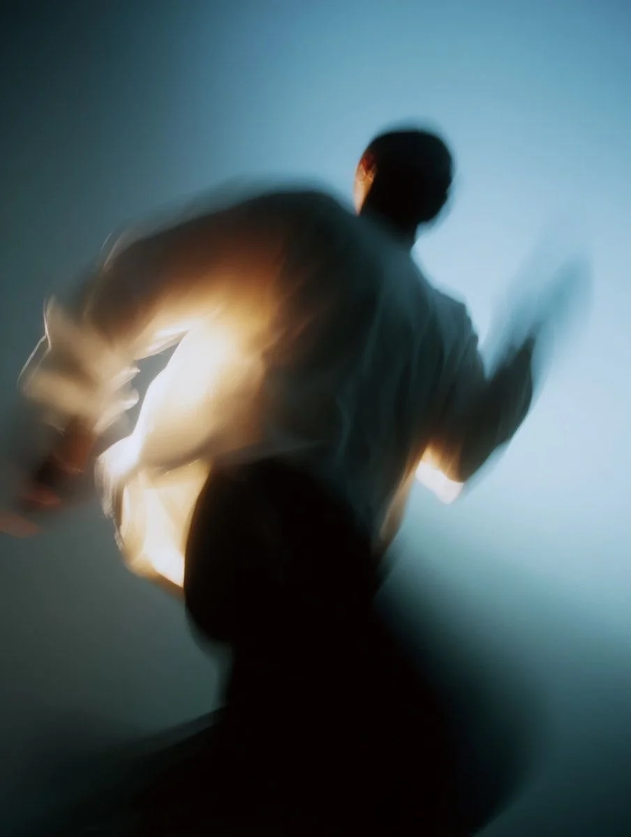 A blurry silhouette of a person running against a blue background.